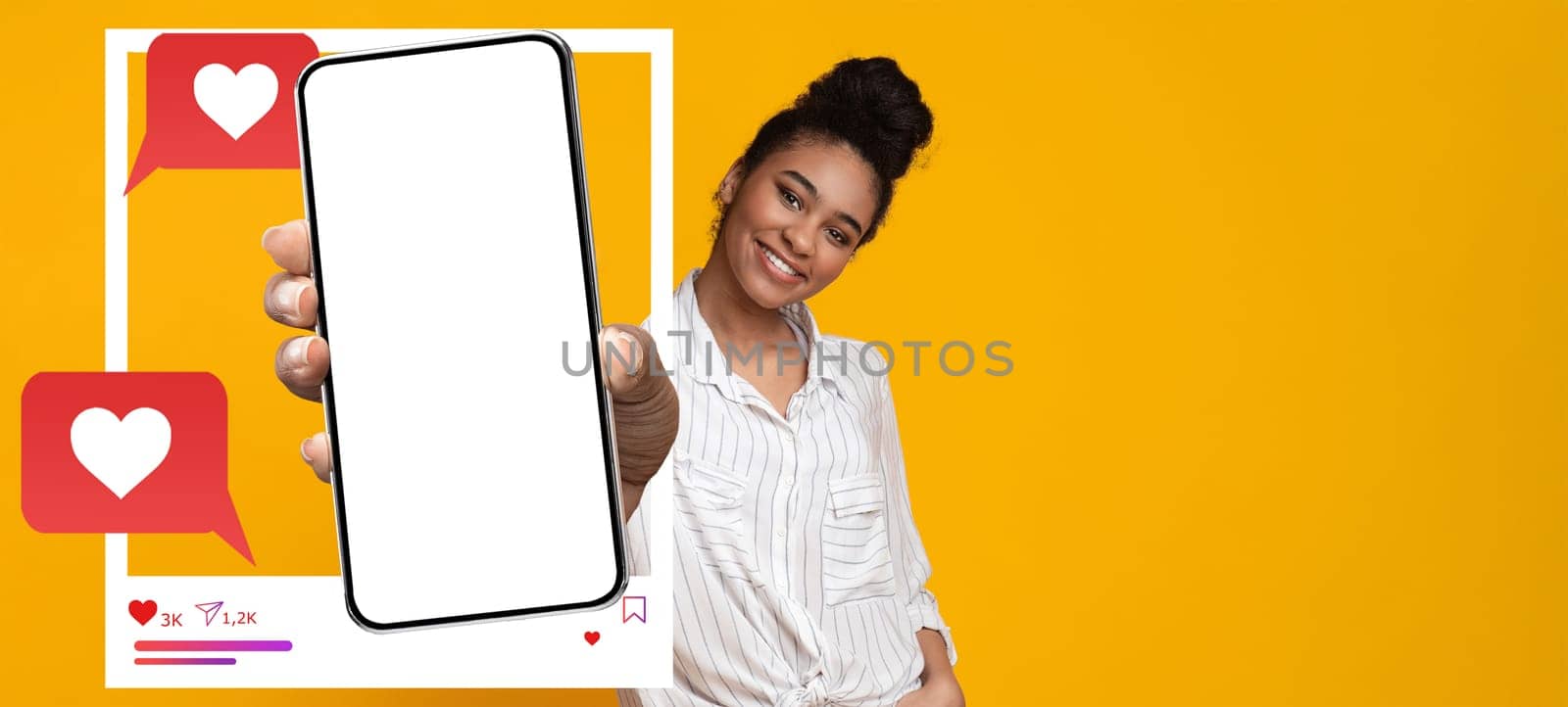A confident influencer holds a blank smartphone against a vibrant yellow background. She interacts with her online audience, representing modern social media engagement and communication.