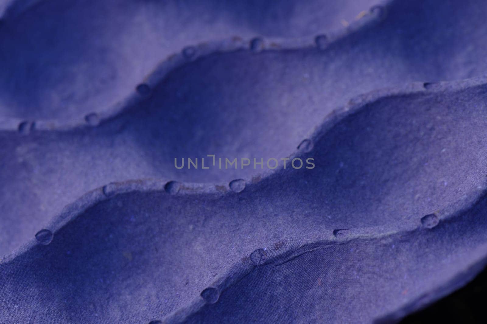 Close-up view of a deep blue fabric showcasing captivating wave-like textures and tiny droplets.