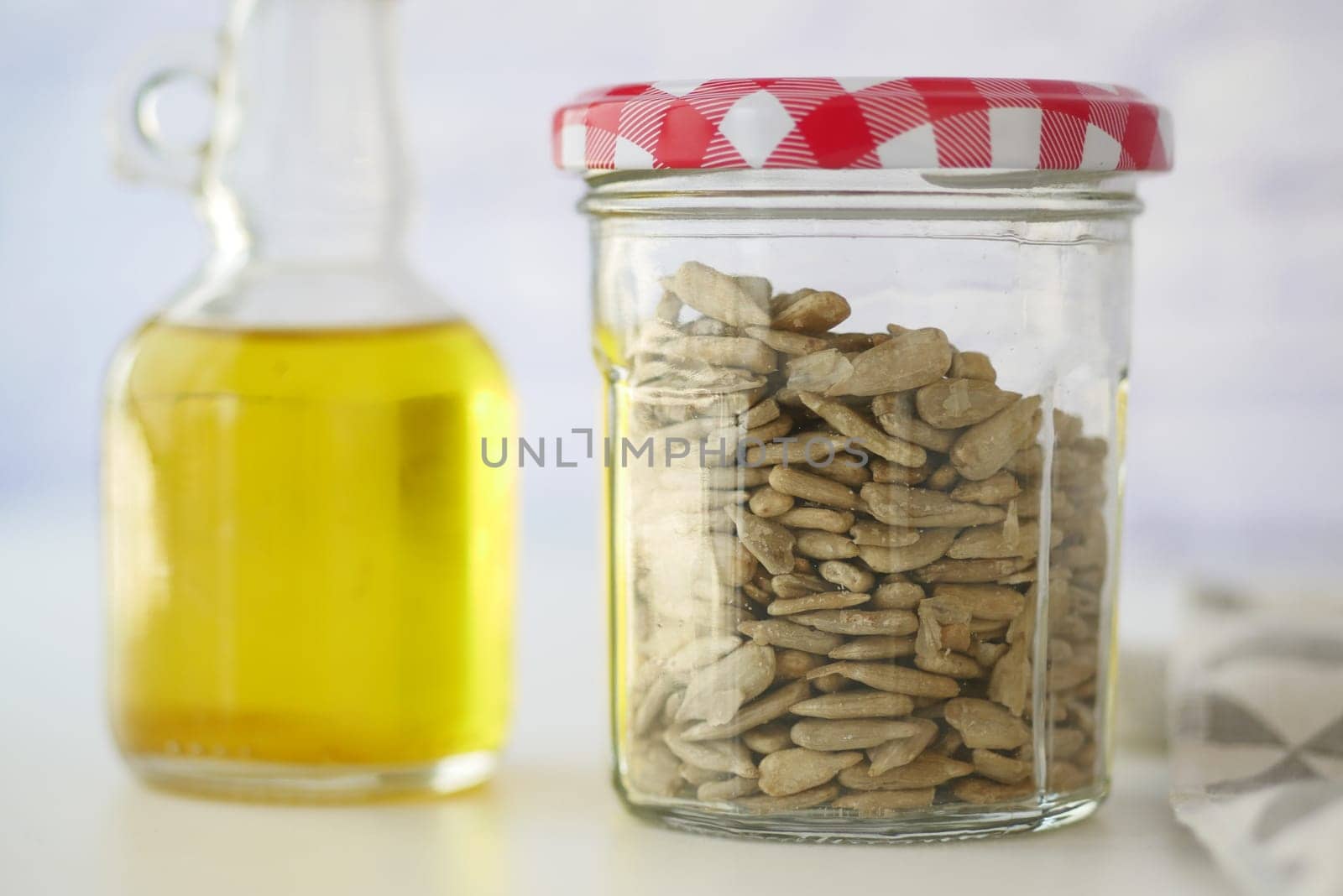 A jar filled with sunflower seeds sits next to a bottle of oil.