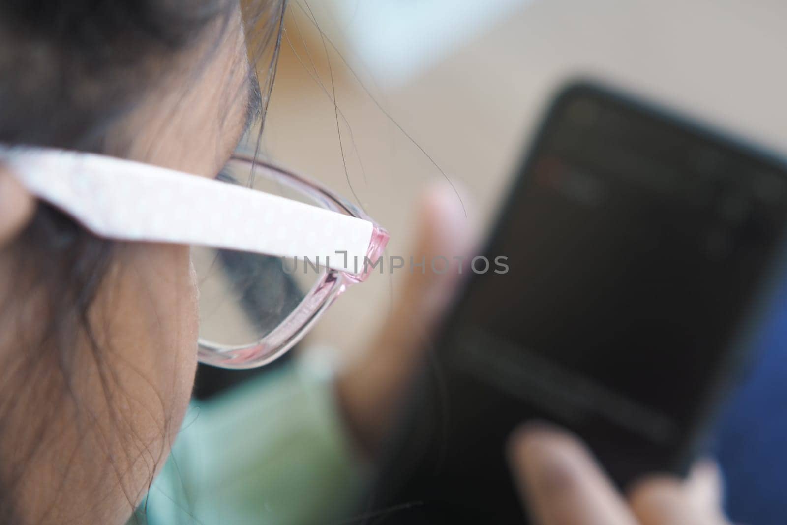 a child using a smartphone while wearing glasses indoors,