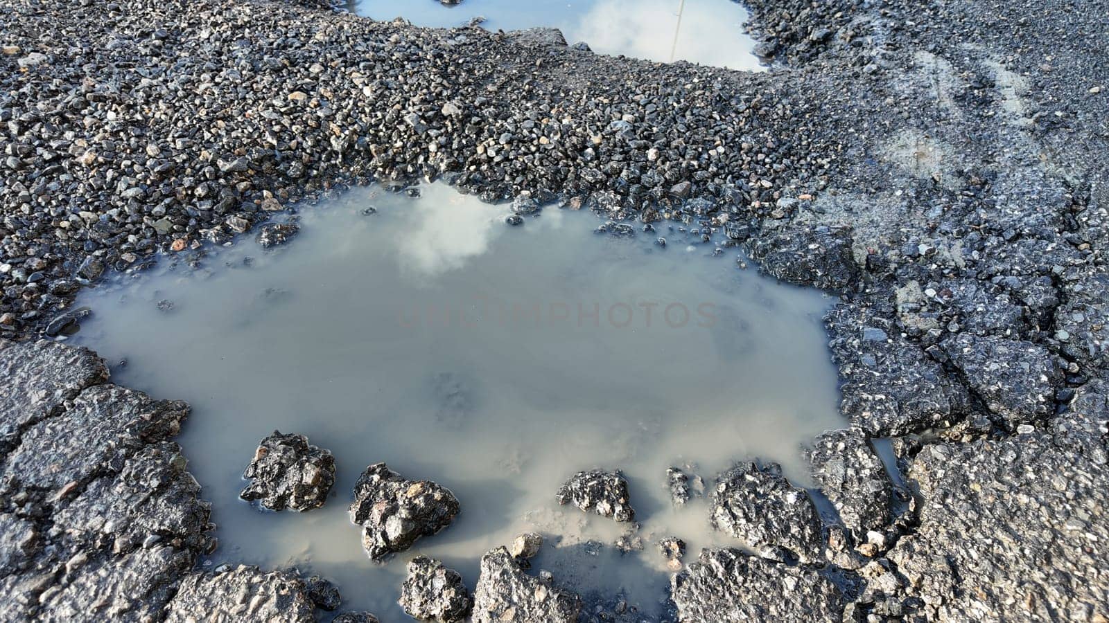 Water accumulates in a damaged road surface following recent rain.