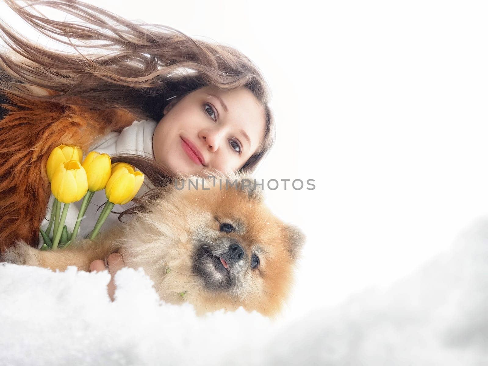 A mother and daughter share a happy moment as they walk through a sunny field filled with dandelions and blooming flowers, creating joyful memories.
