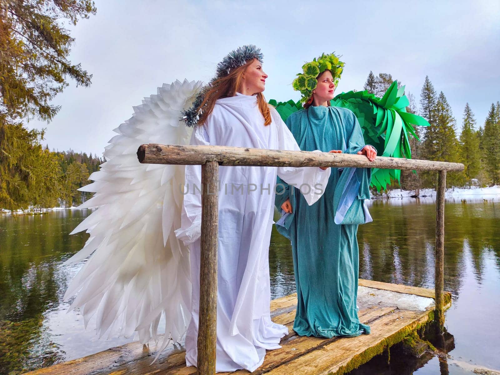 Two girls dressed in white and green stand gracefully by the tranquil lake, embodying the magical transition from winter to spring.