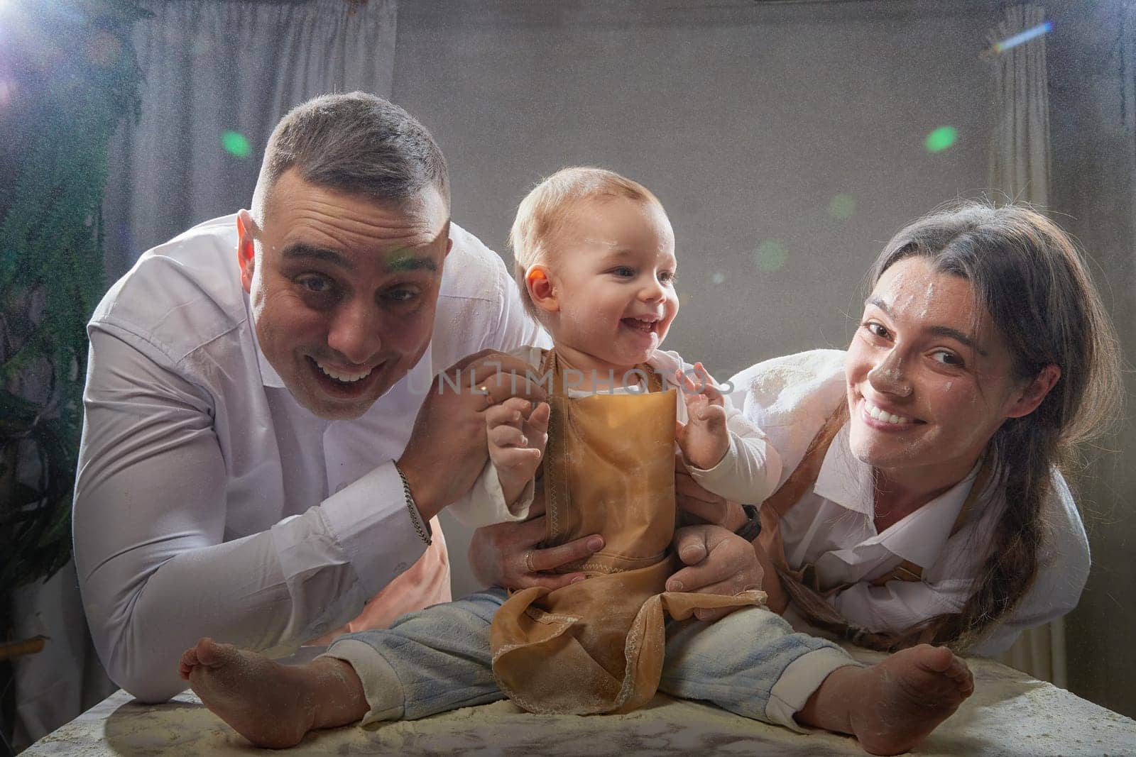 A family enjoys a fun cooking session, playfully covered in flour while engaging with their little ones in warm kitchen