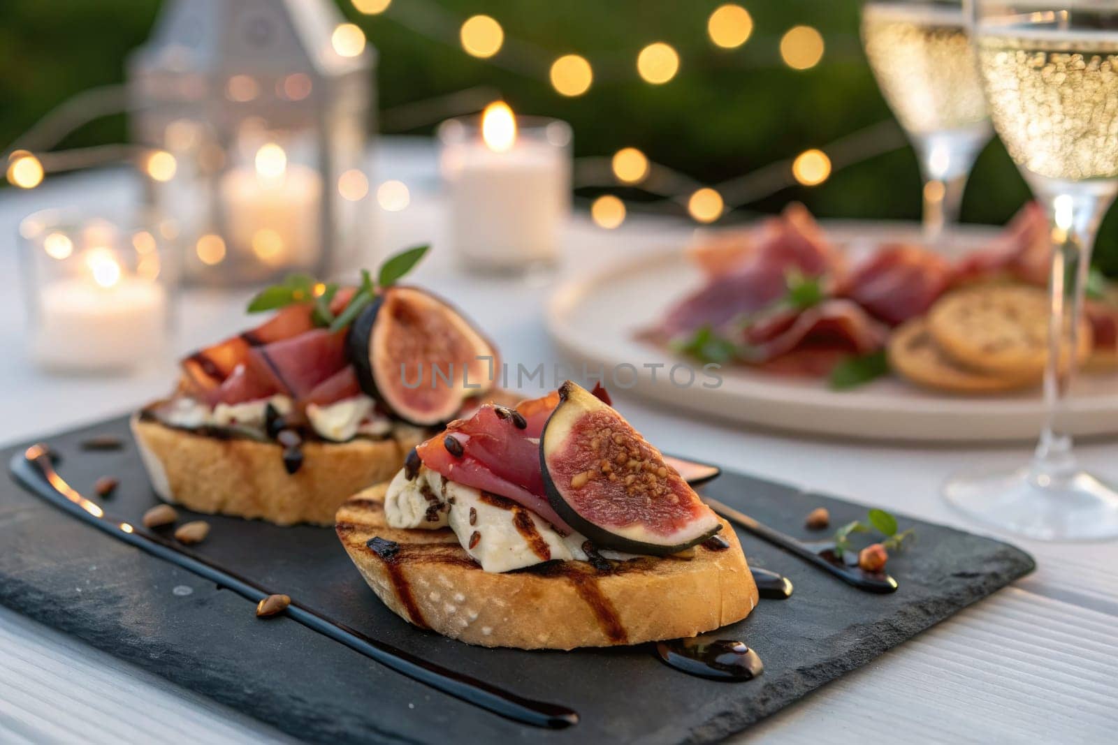 Plates are adorned with gourmet bruschetta topped with fresh figs, served alongside sparkling drinks and candles. The soft glow creates a cozy atmosphere for an evening gathering.