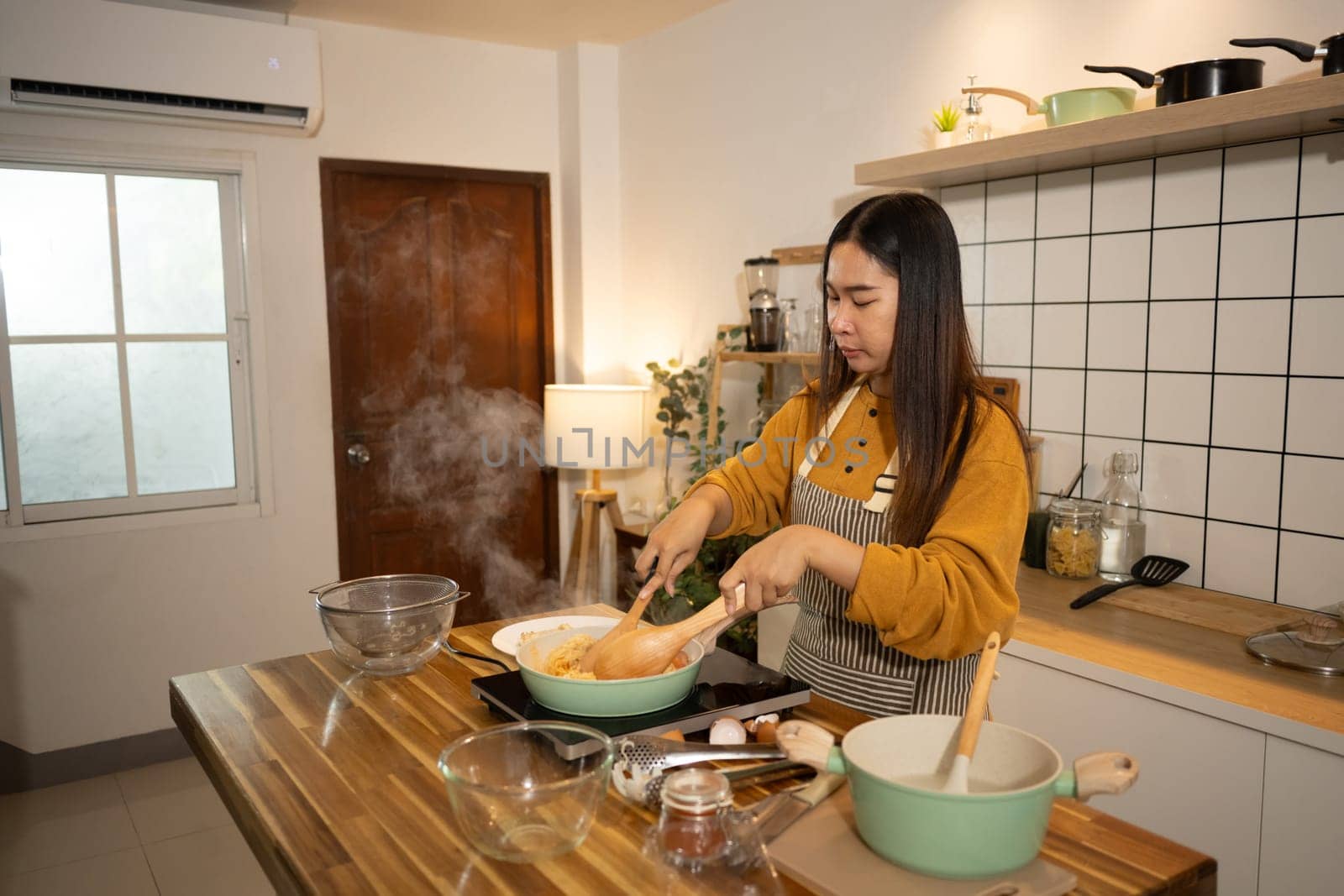 Happy young woman preparing a delicious homemade meal in cozy kitchen.