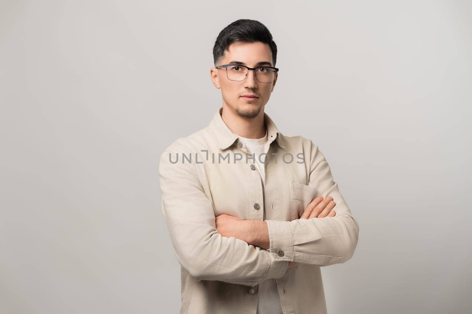 Handsome confident man, IT specialist and system administrator in neat clothes, stands with arms crossed, wearing eyeglasses, inspiring trust in web security and data protection.