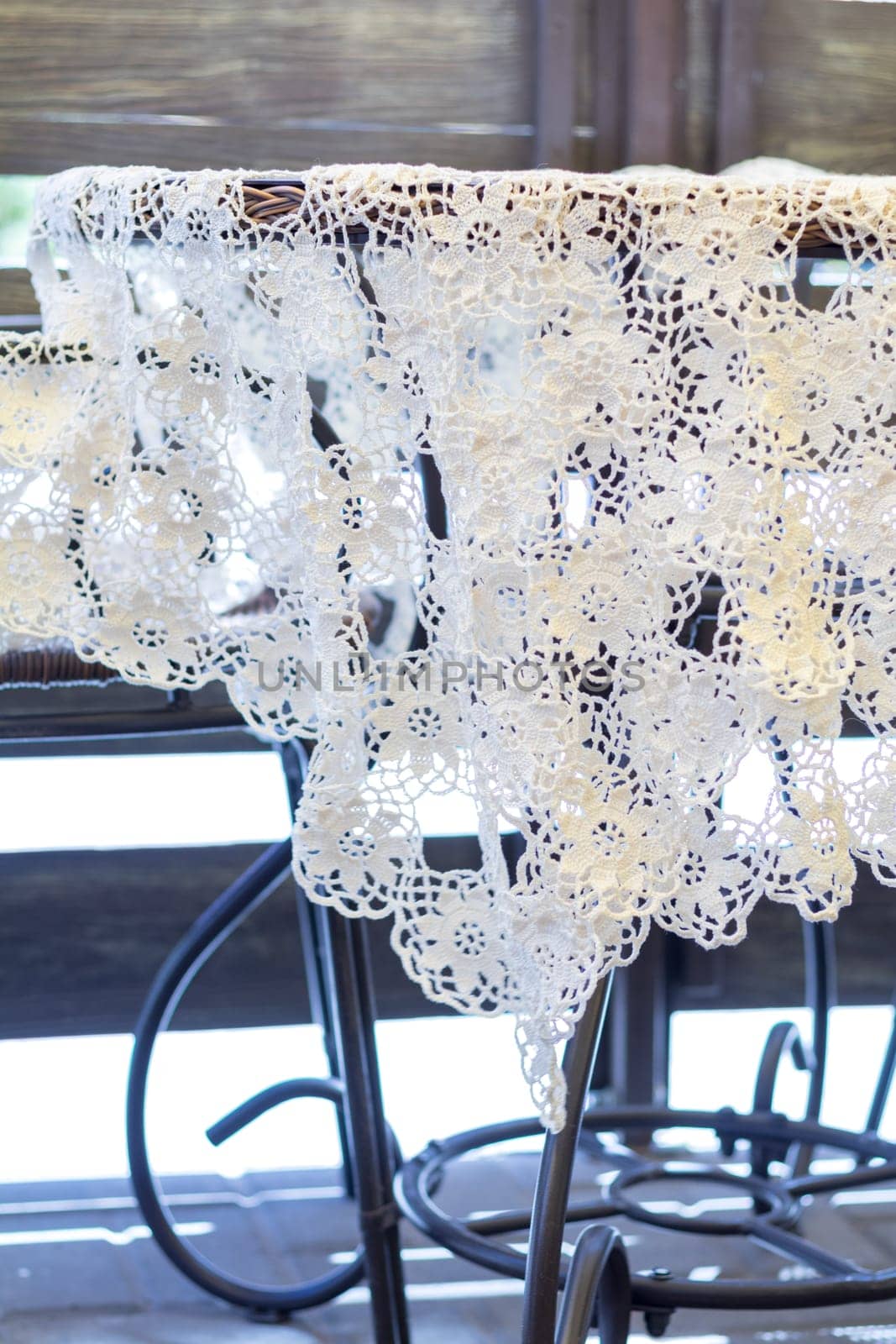 Delicate white crochet tablecloth draped over a wicker table on a balcony, creating a cozy and charming atmosphere