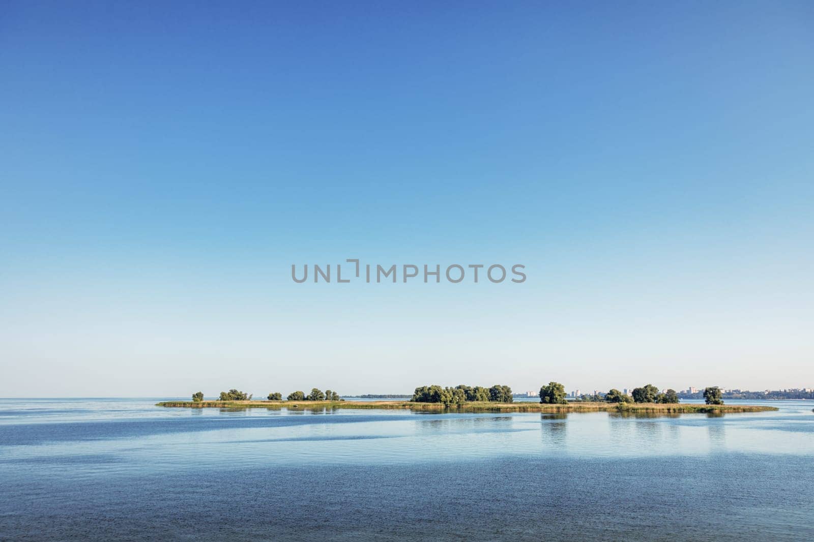 Beautiful landscape showing small islands reflecting on the calm water of a river under a clear blue sky