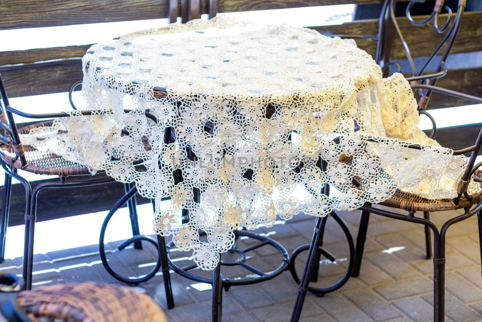Cozy outdoor cafe table featuring a delicate, handmade crochet tablecloth, creating a charming and inviting atmosphere