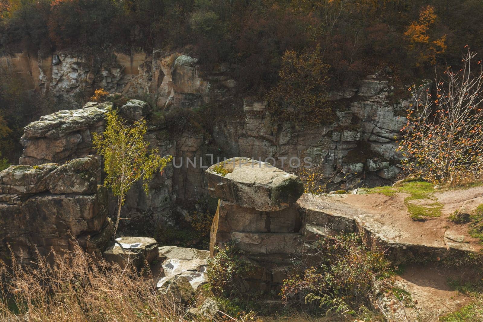 Moss covered rocks and vibrant trees create a breathtaking autumn landscape within an old stone quarry, showcasing nature's colorful beauty