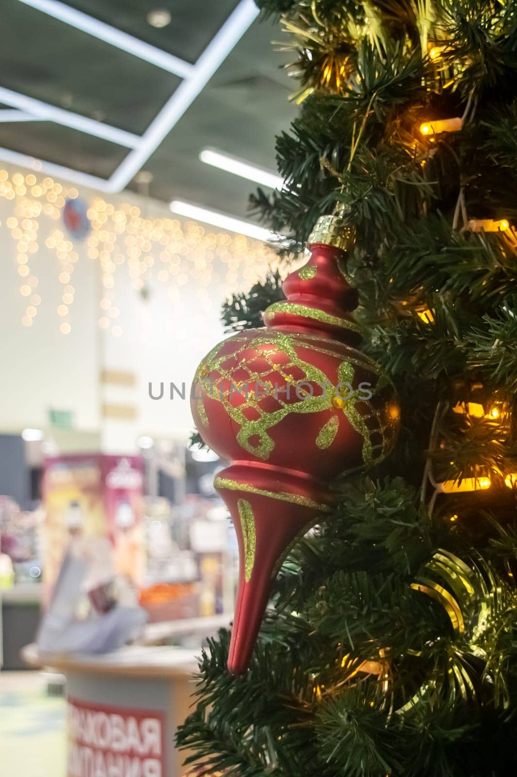 This is a closeup image of a beautifully decorated Christmas tree featuring a shiny red ornament that is hanging from its branches