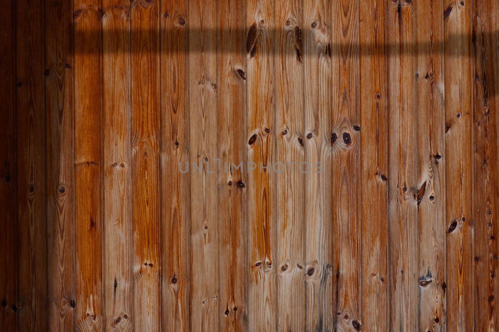 Sunlight streams through, casting soft shadows across the rugged surface of the weathered wooden wall, showcasing its rich hues and unique grain patterns that tell stories of time.