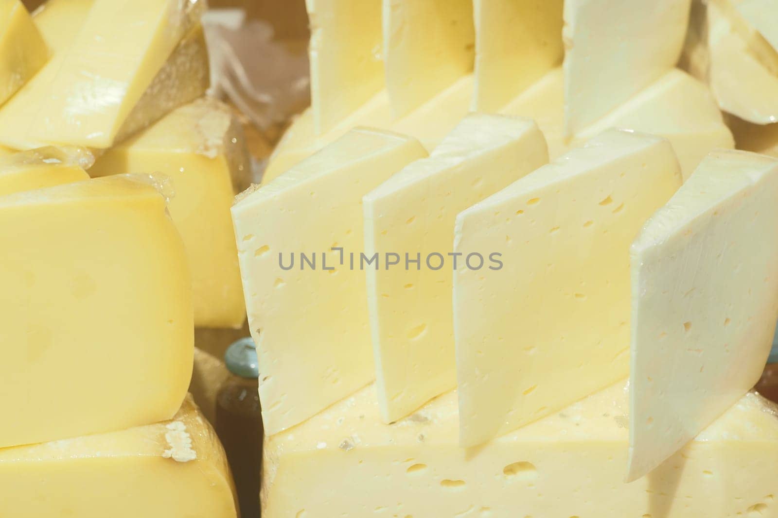 Various types of artisanal cheese are arranged in a market stall.