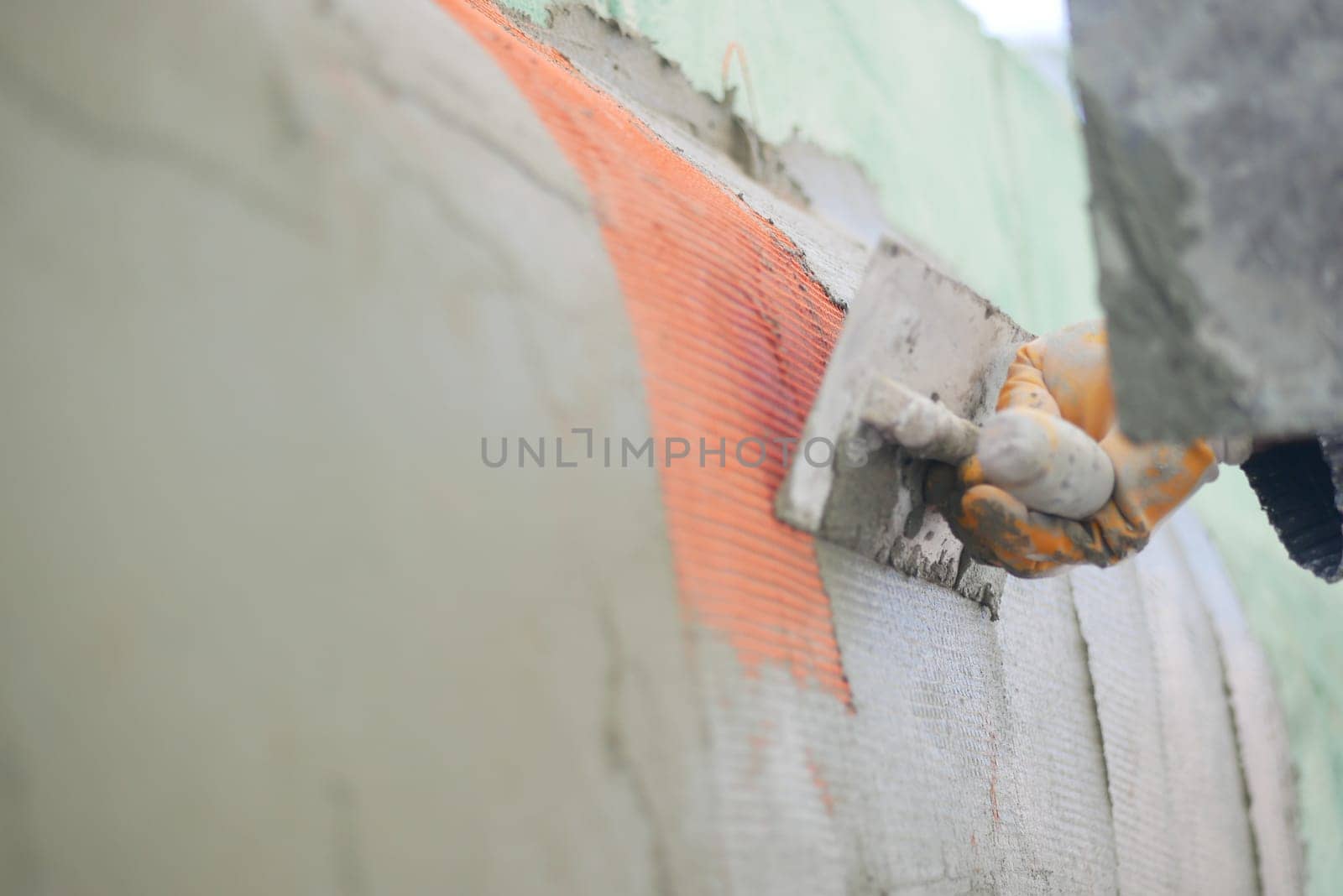 A construction worker smooths plaster on a wall during renovation.