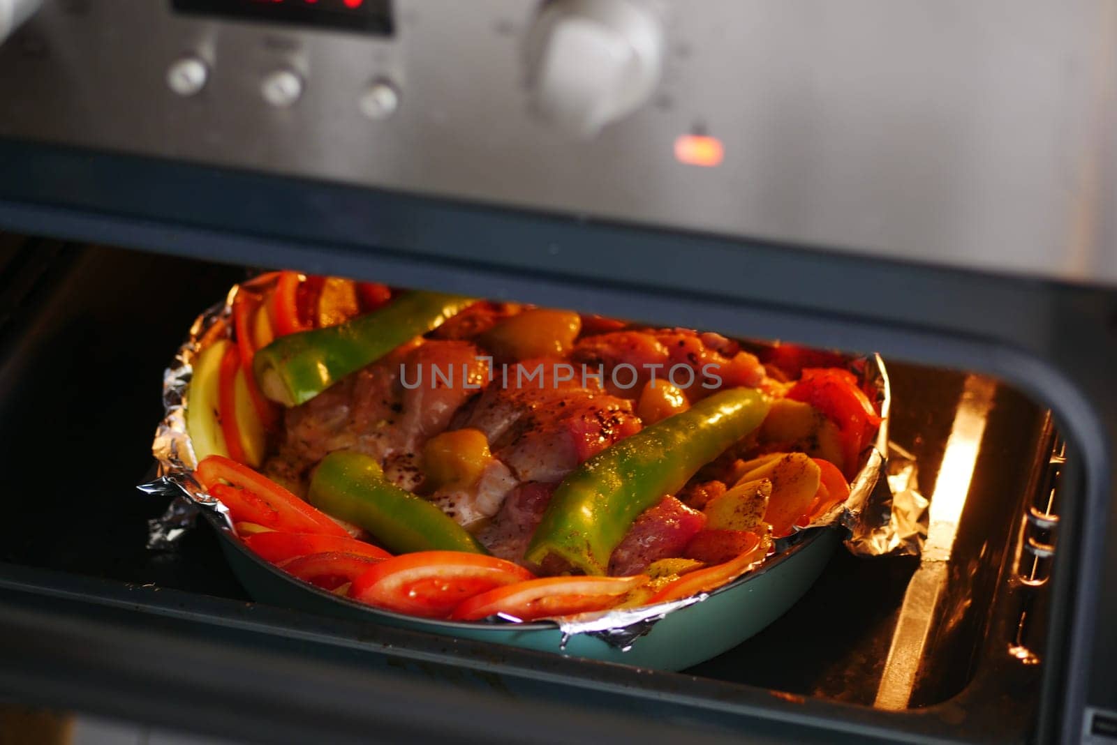 A colorful dish of meat and vegetables cooks slowly in the oven.