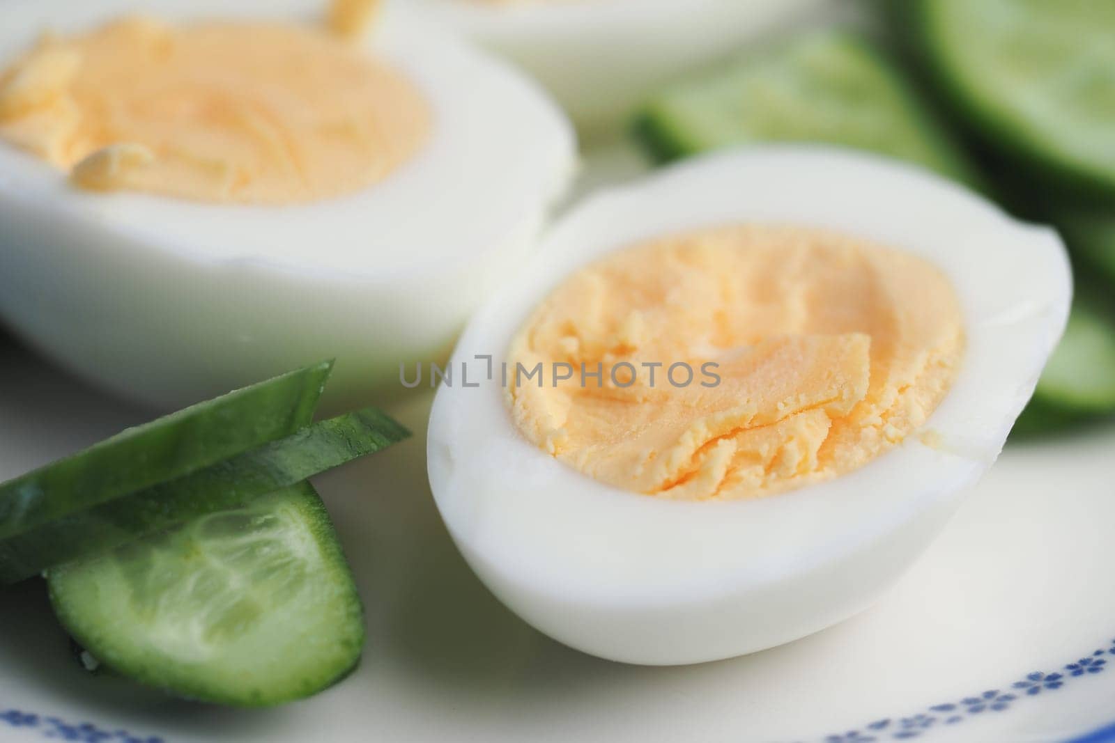Sliced hard-boiled eggs are arranged on a plate with cucumber.