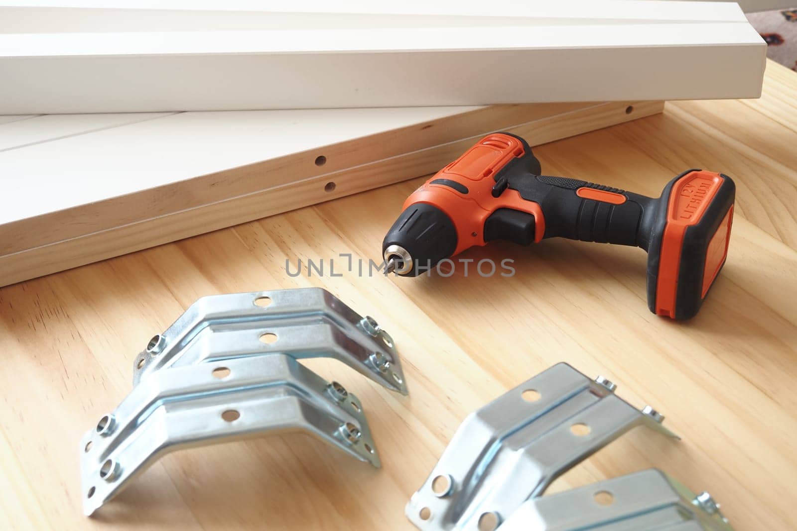 Various tools and brackets arranged on a wooden surface for DIY task.