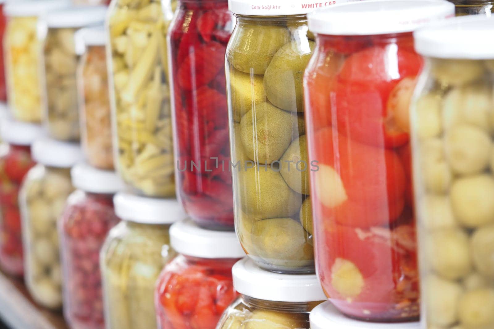 Rows of jars filled with vibrant pickled vegetables stand neatly arranged.