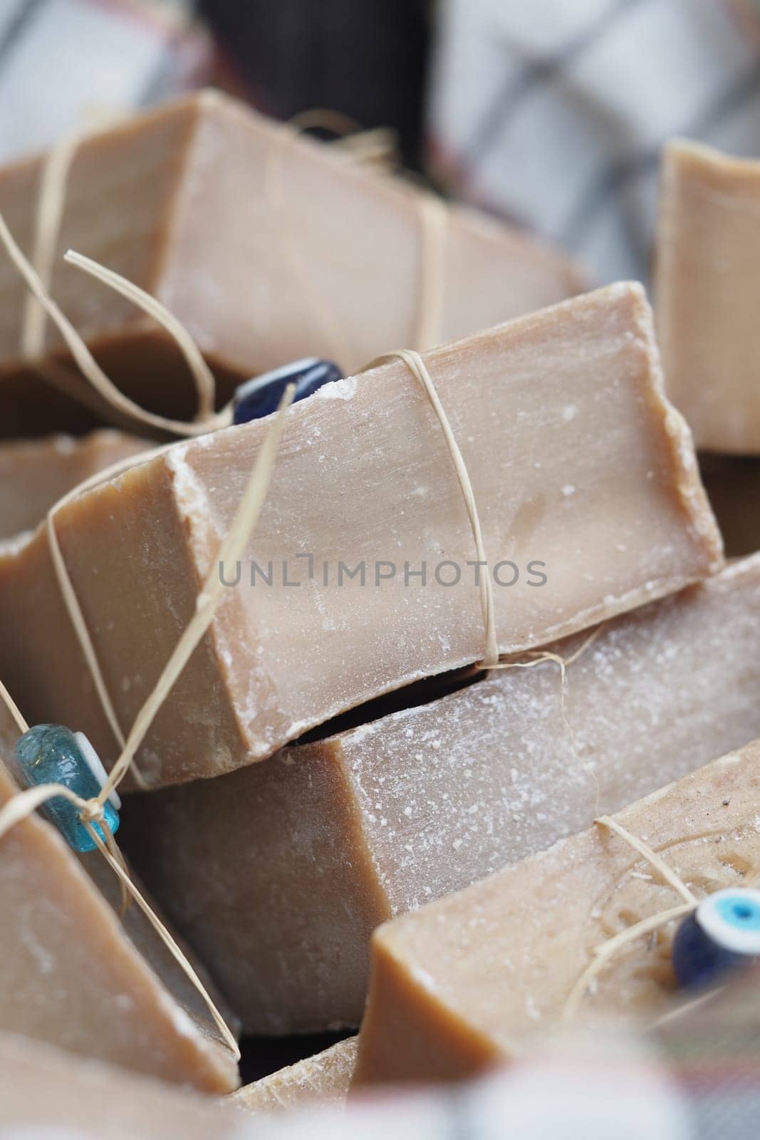 Artisan soap bars are stacked with decorative beads and twine in a market.