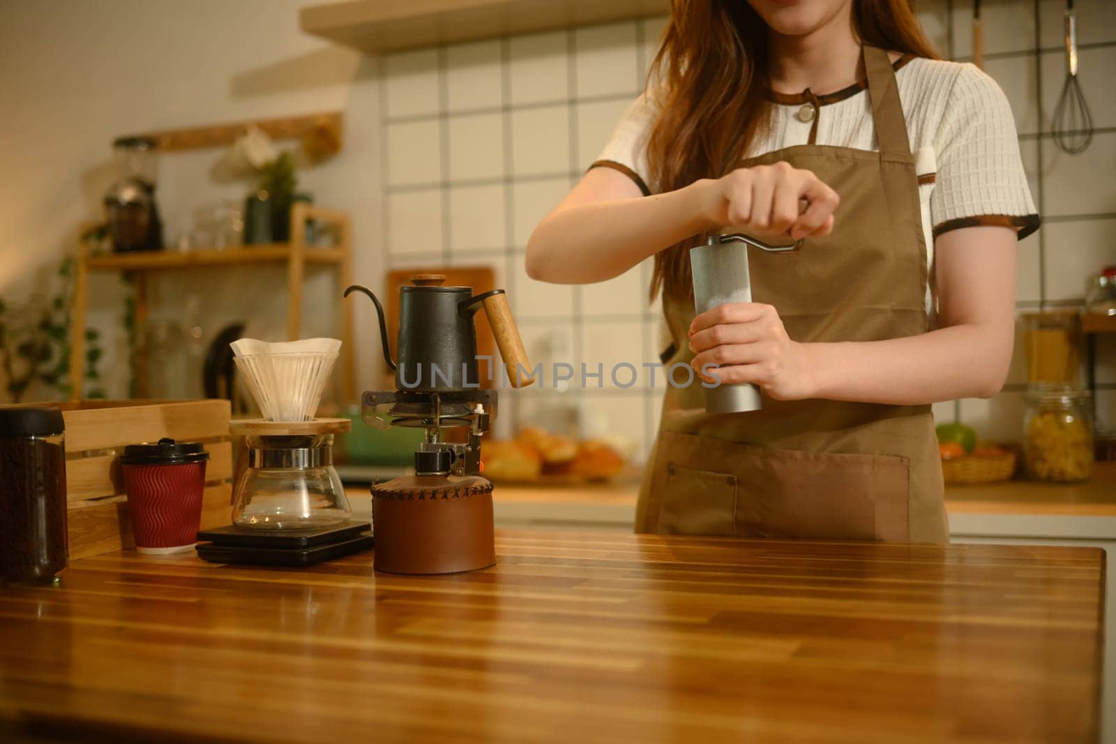 Close up shot of grinding fresh coffee beans with hand grinder at kitchen counter.