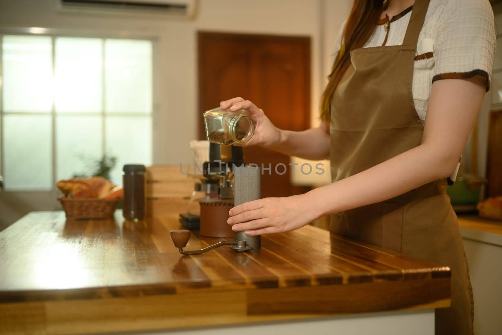 Close up of woman preparing handcrafted coffee on a wooden kitchen counter.