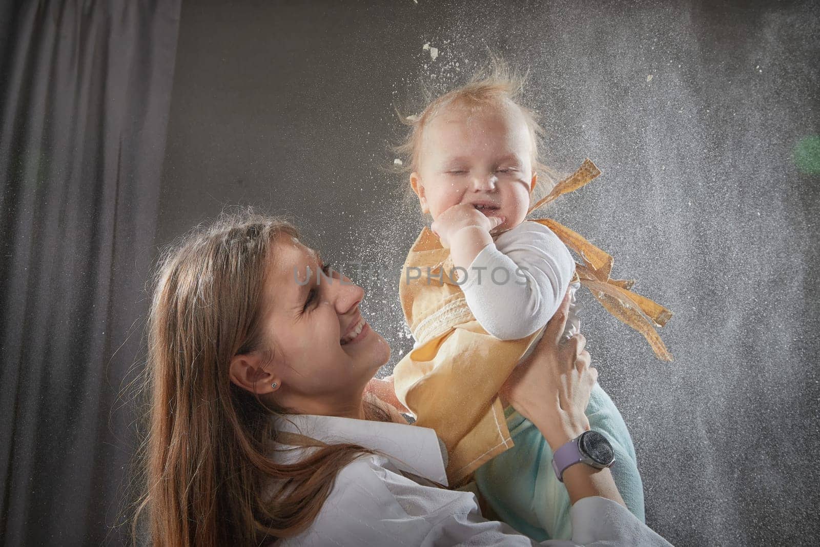 A mother and daughter joyfully engage in a flour-filled moment, creating memories in a cozy kitchen setting.