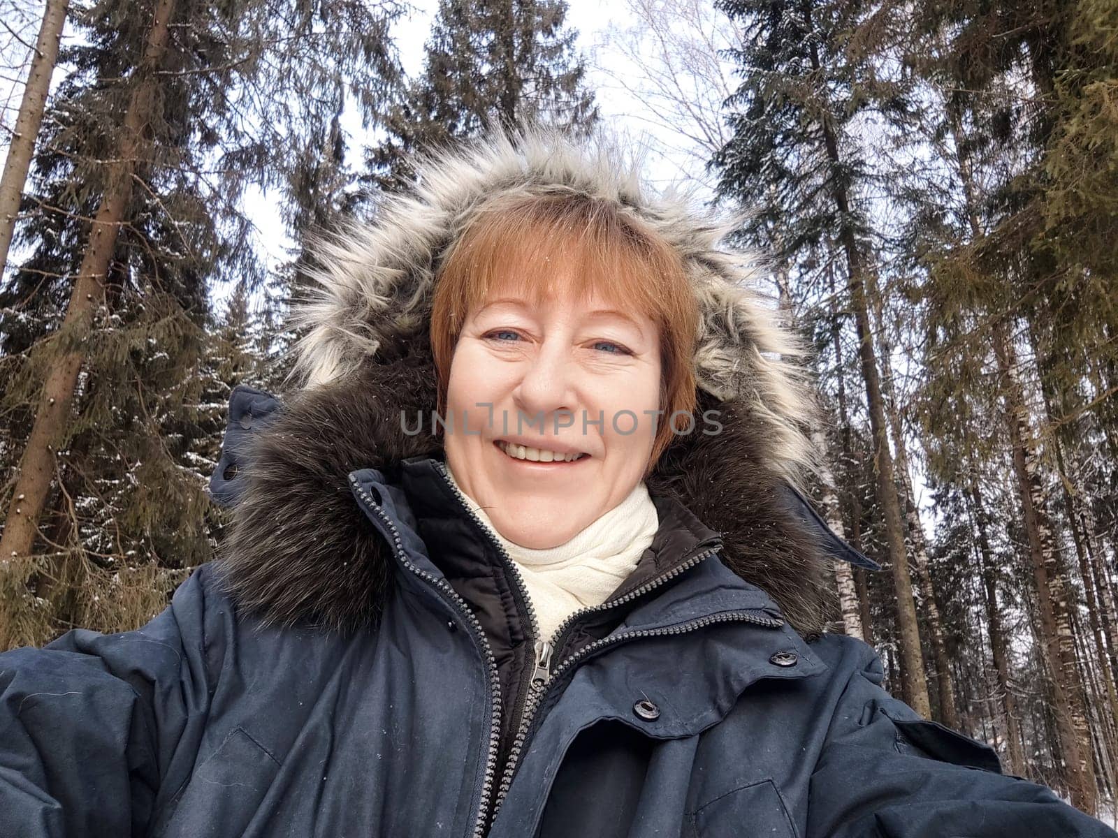 Tourist captures a joyful moment in a snowy forest, showcasing her excitement for winter excursions and travel adventures in nature.