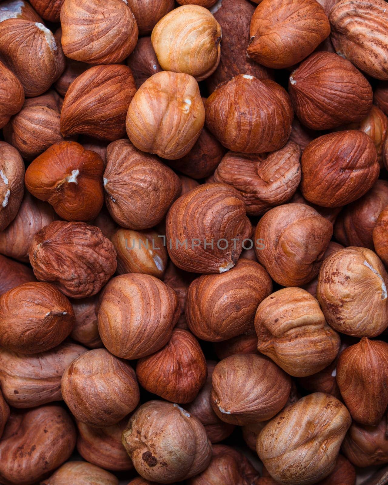 A detailed close-up of whole hazelnuts in their shells, showcasing their natural texture and warm brown tones. Perfect for food backgrounds and nut-related themes