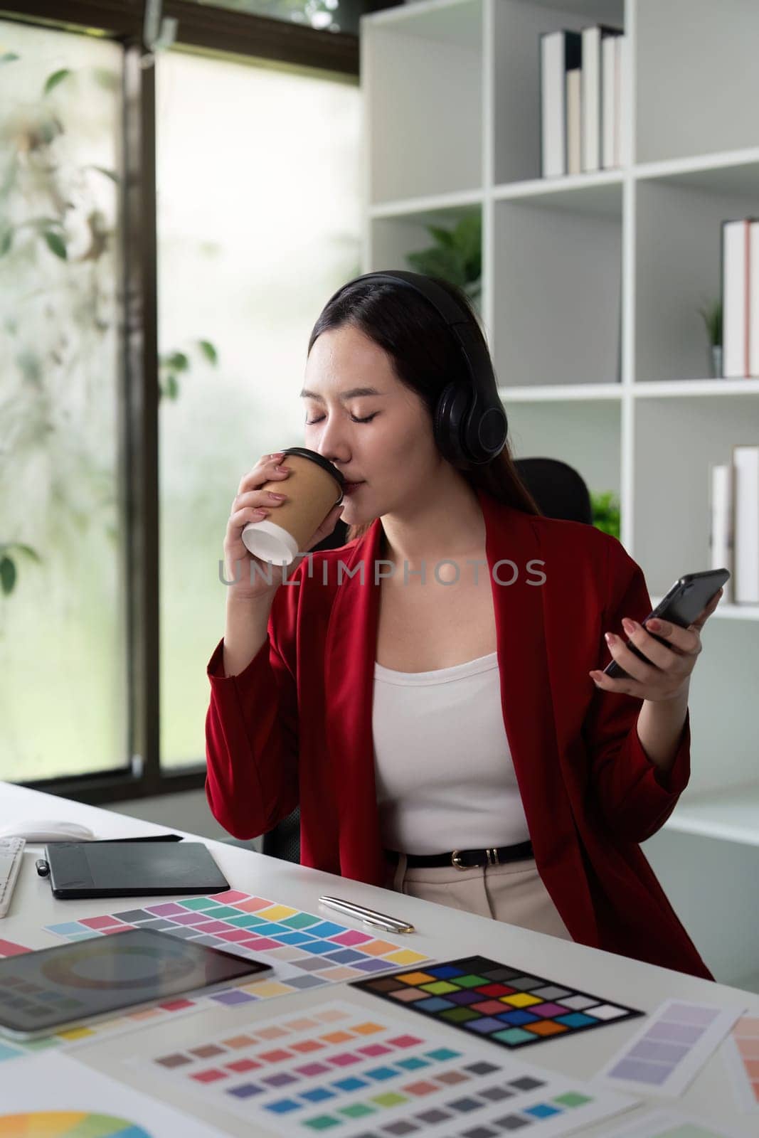 Capturing a moment of reflection, this image shows a designer enjoying coffee, immersed in thoughts about color and design in a modern workspace.