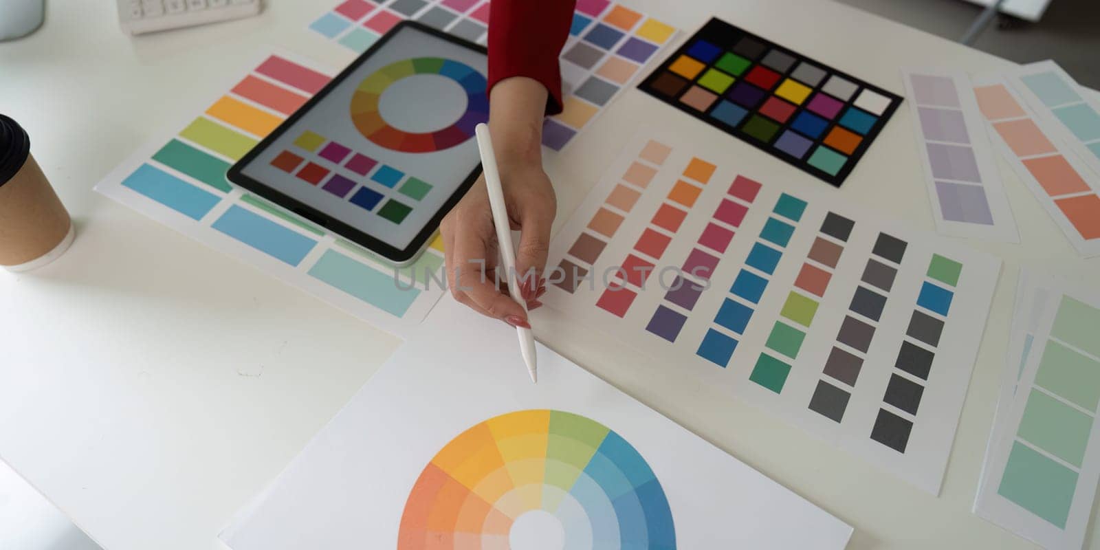 Focusing on a creative workspace, the image captures a designer choosing colors from a palette, highlighting the artistic workflow and inspiration.
