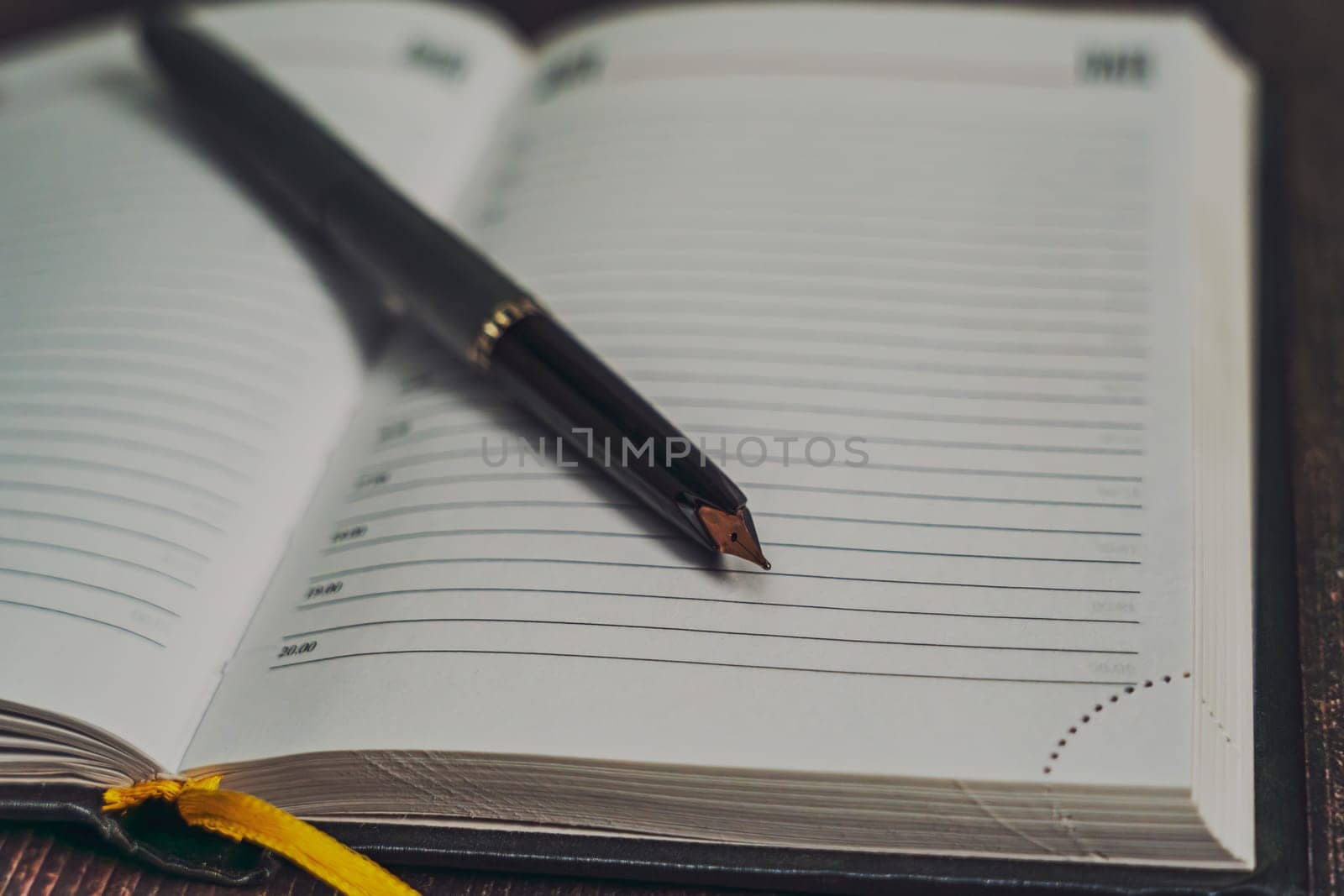 A close-up of a black fountain pen resting on an open planner with lined pages, ready for writing. A concept of planning, journaling, and organization