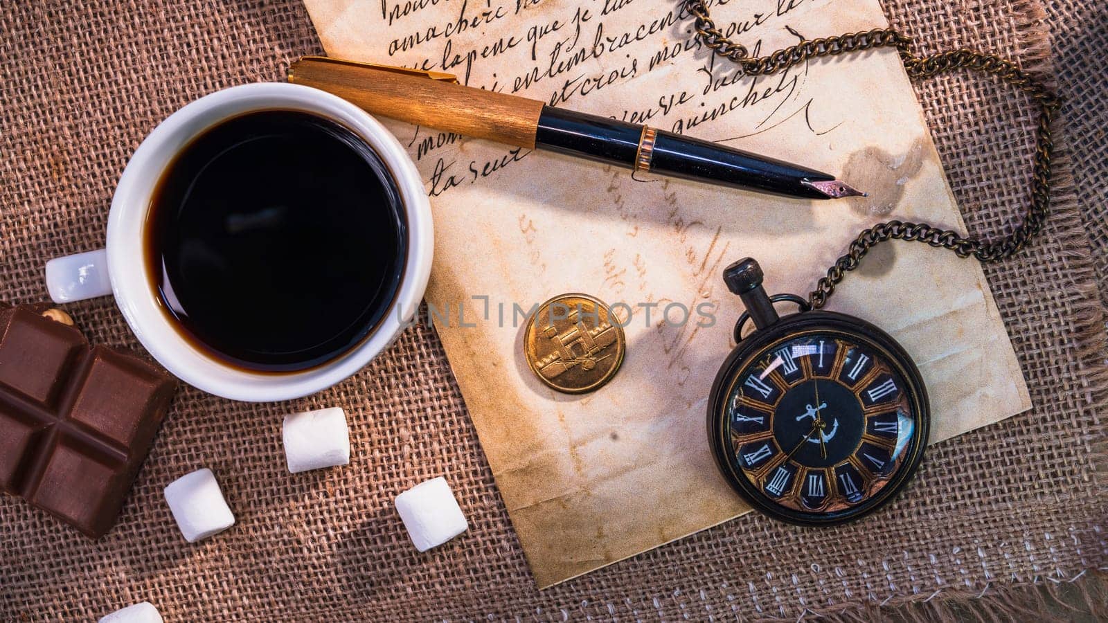 Vintage still life with a cup of coffee, a pocket watch, handwritten letters, a fountain pen, and chocolate on a burlap background. Warm and nostalgic atmosphere with retro elements