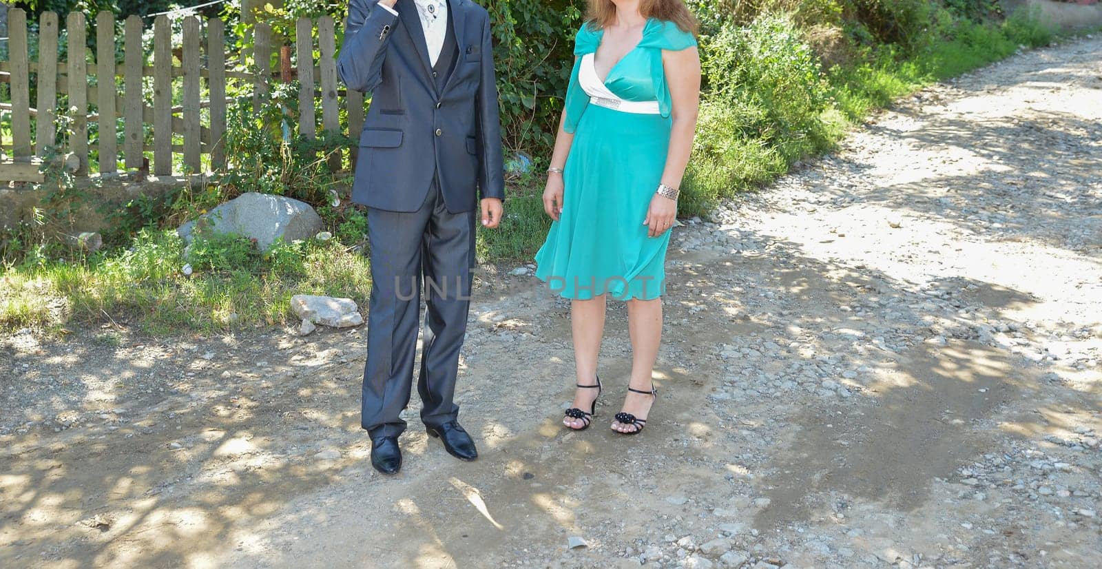 A suited man and a woman in a turquoise dress pause for a moment, capturing the elegance of the celebration.