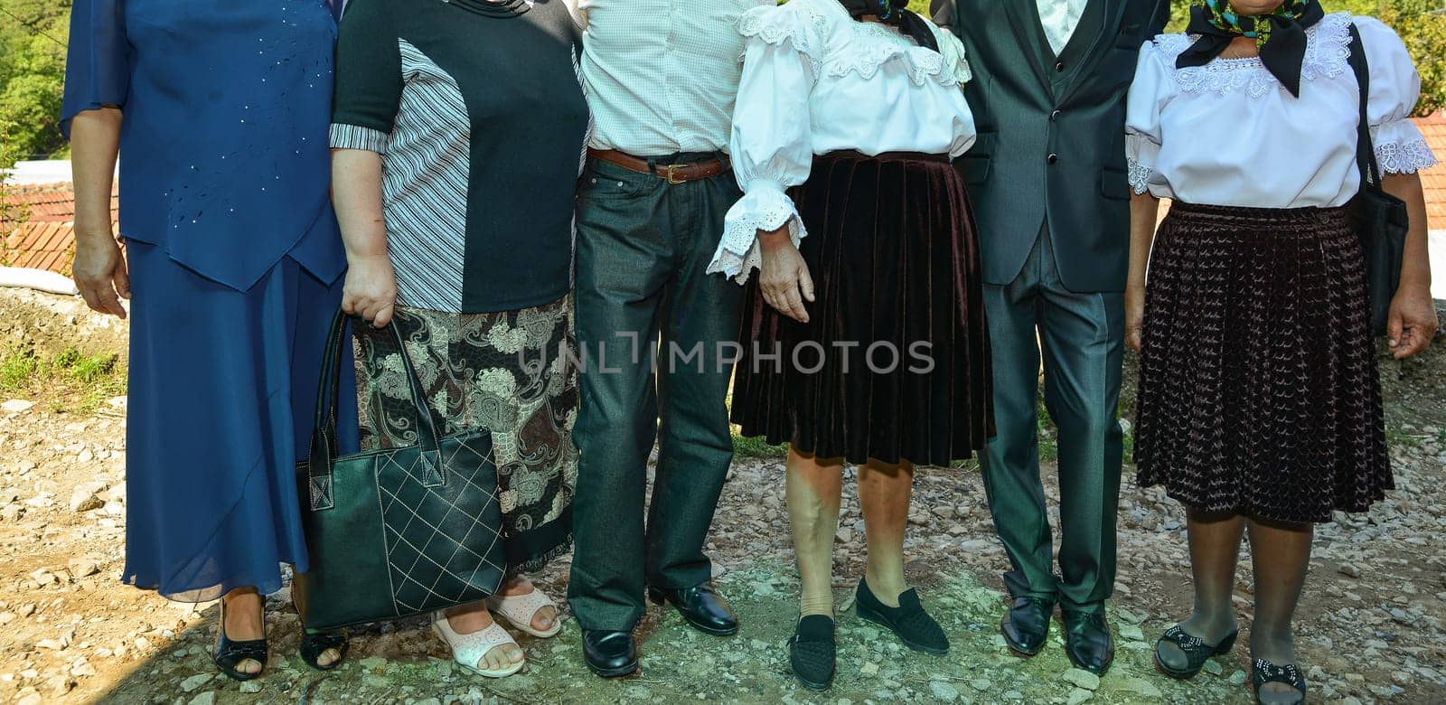 A group of people stand side by side, each wearing distinct formalwear, sharing in the spirit of the occasion