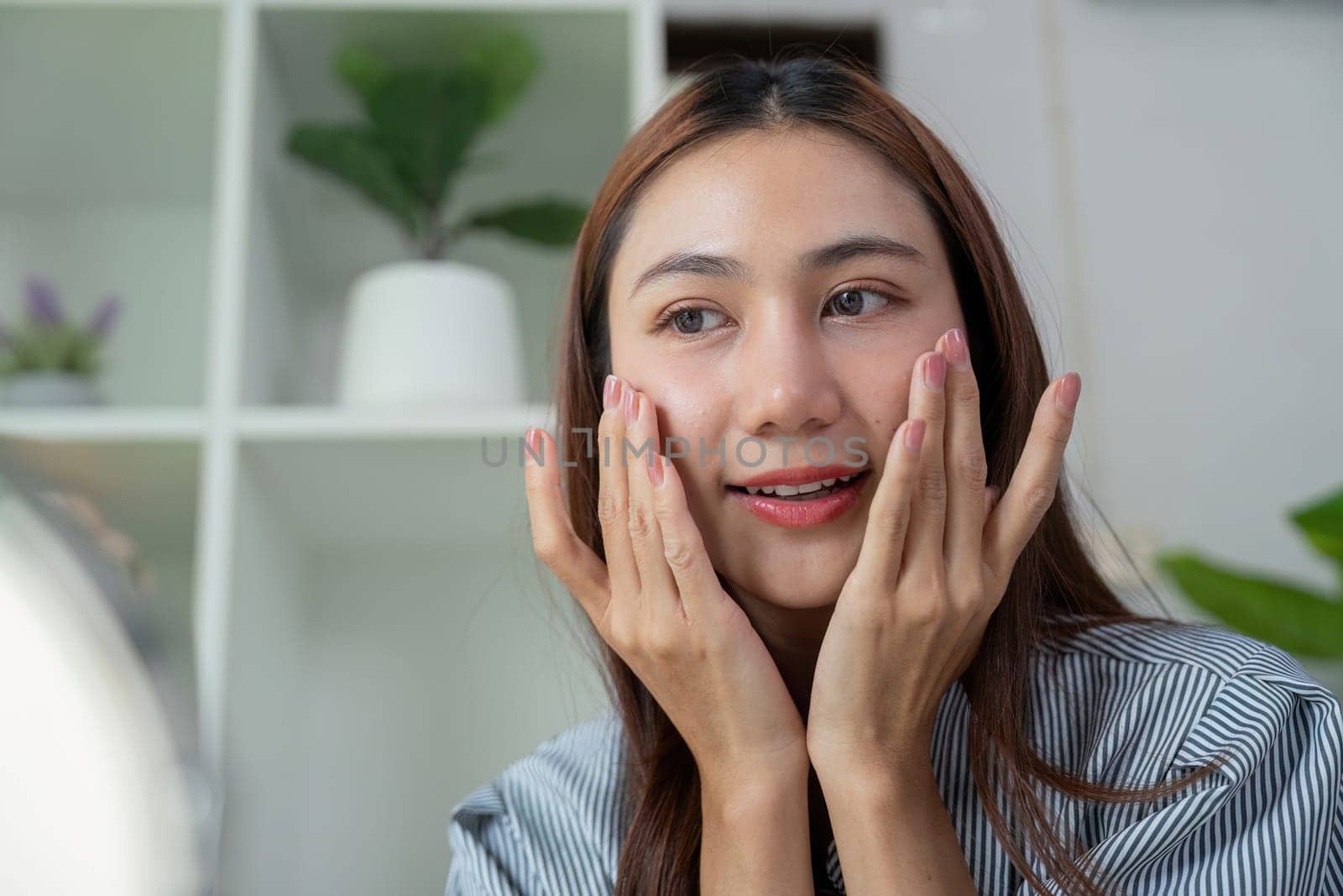 A skincare lover indulges in her routine, applying a product while appreciating her glowing complexion in a serene environment.