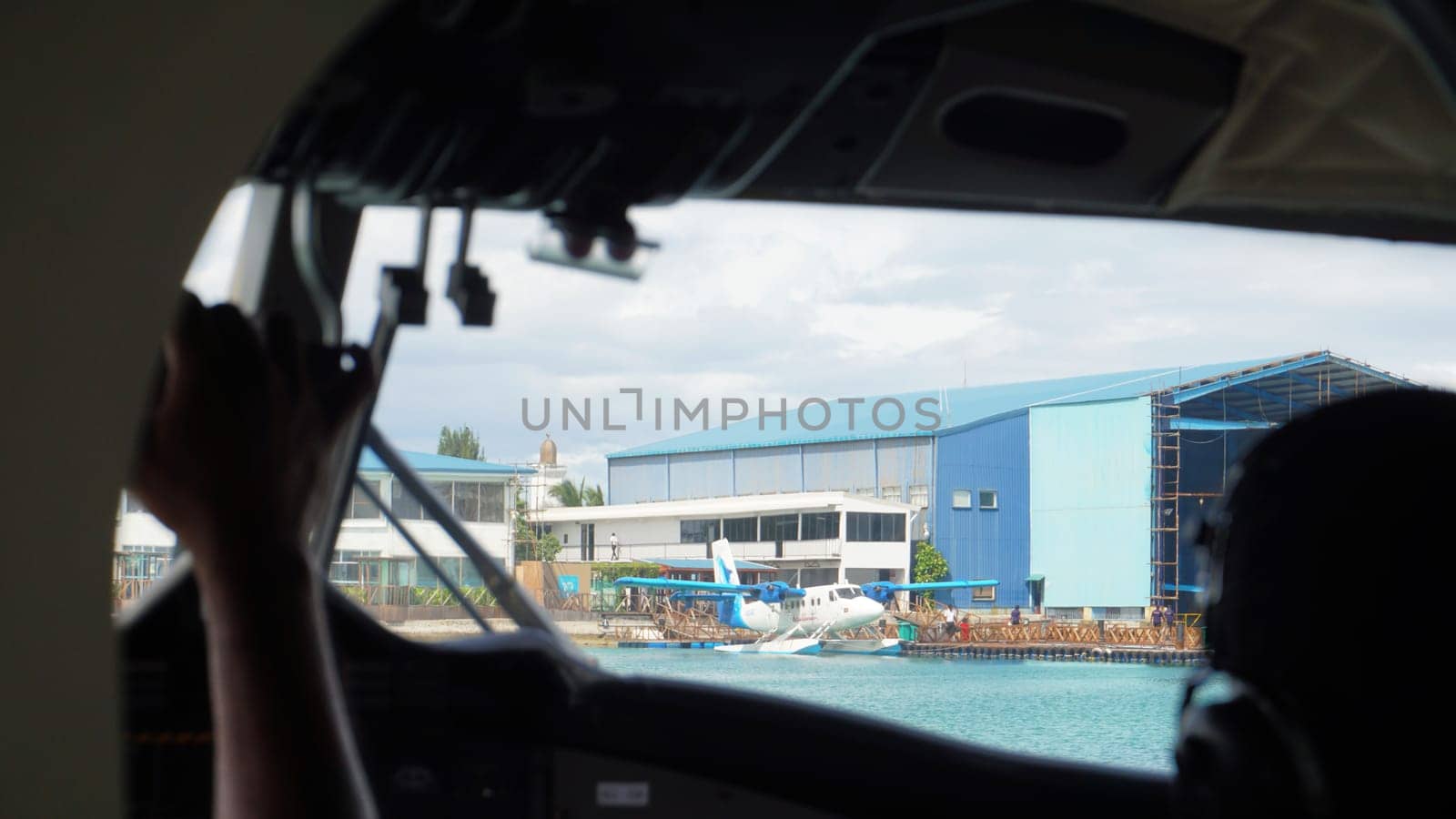 Capturing a stunning view from the cockpit of a seaplane taxiing gracefully near a hangar in the maldives, with the pilot skillfully maneuvering the aircraft through the tropical skies