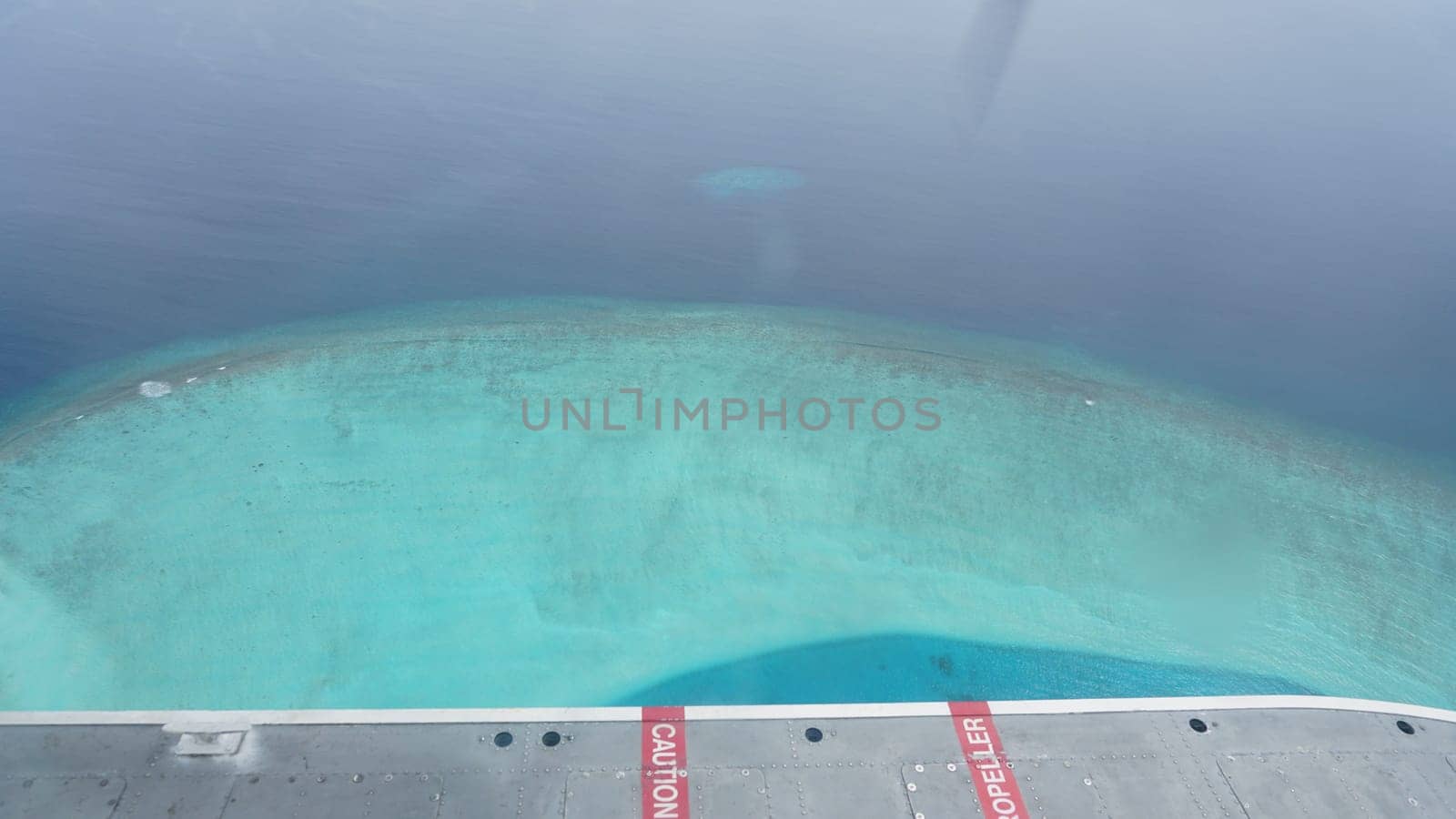 Aerial view of a seaplane flying over a breathtaking tropical island in the maldives, showcasing the vibrant turquoise water and stunning coral reefs below
