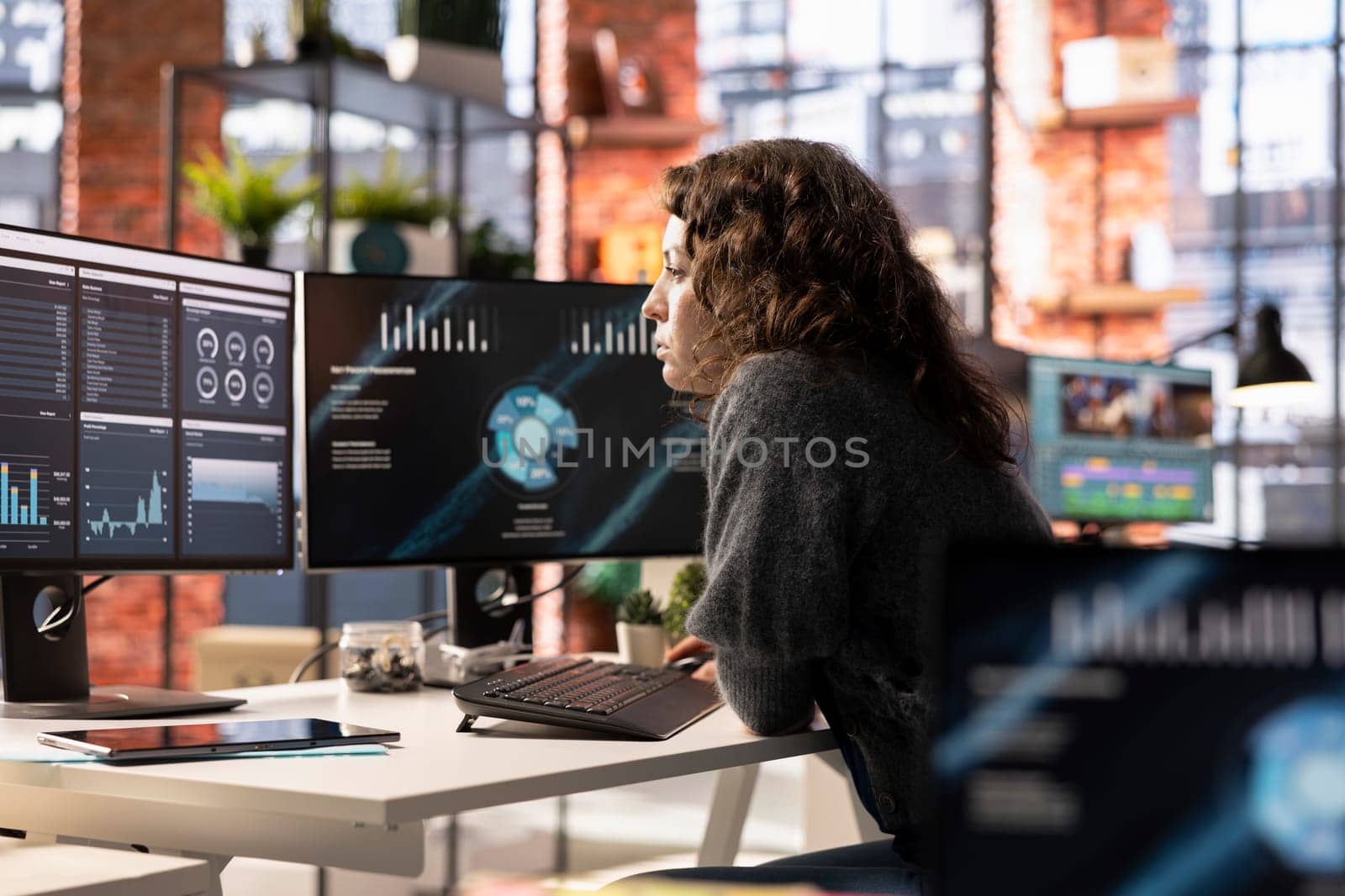 Young woman watching business conference infographics on computer screen, looking over statistics on online portfolio. Analyst in apartment looking at business presentation dashboard.