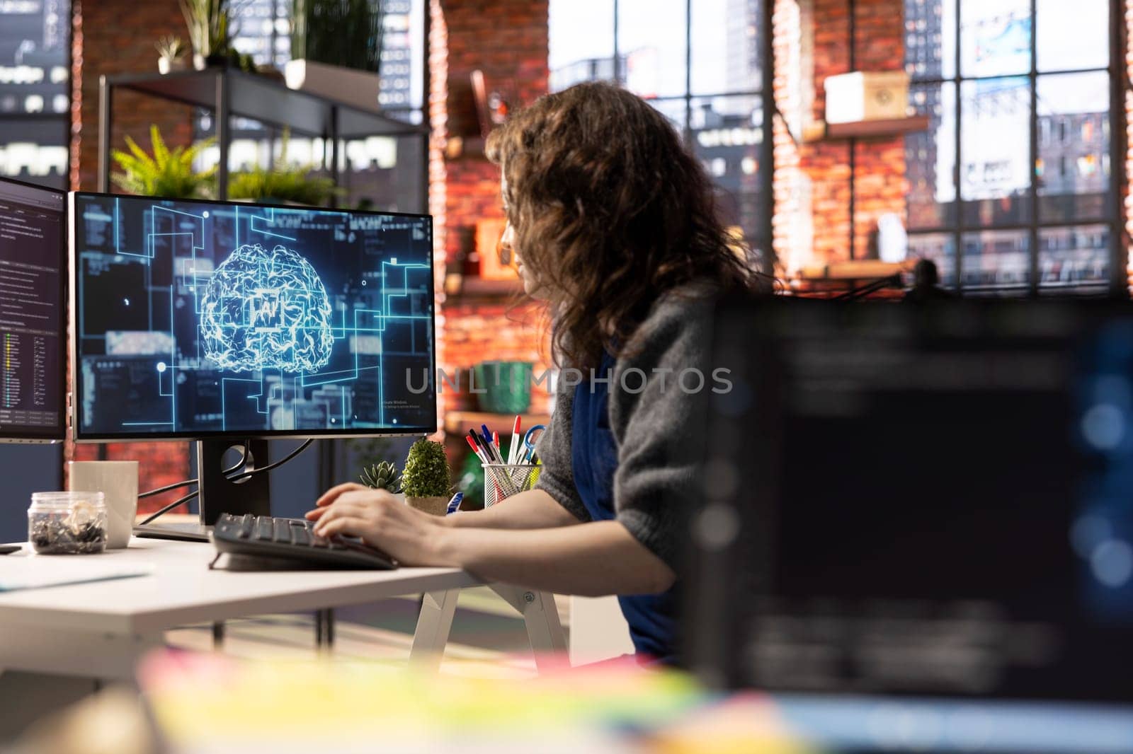 Teleworking developer using computer for artificial intelligence computing through self learning algorithms. Agency IT engineer works with AI deep neural networks on desktop PC.