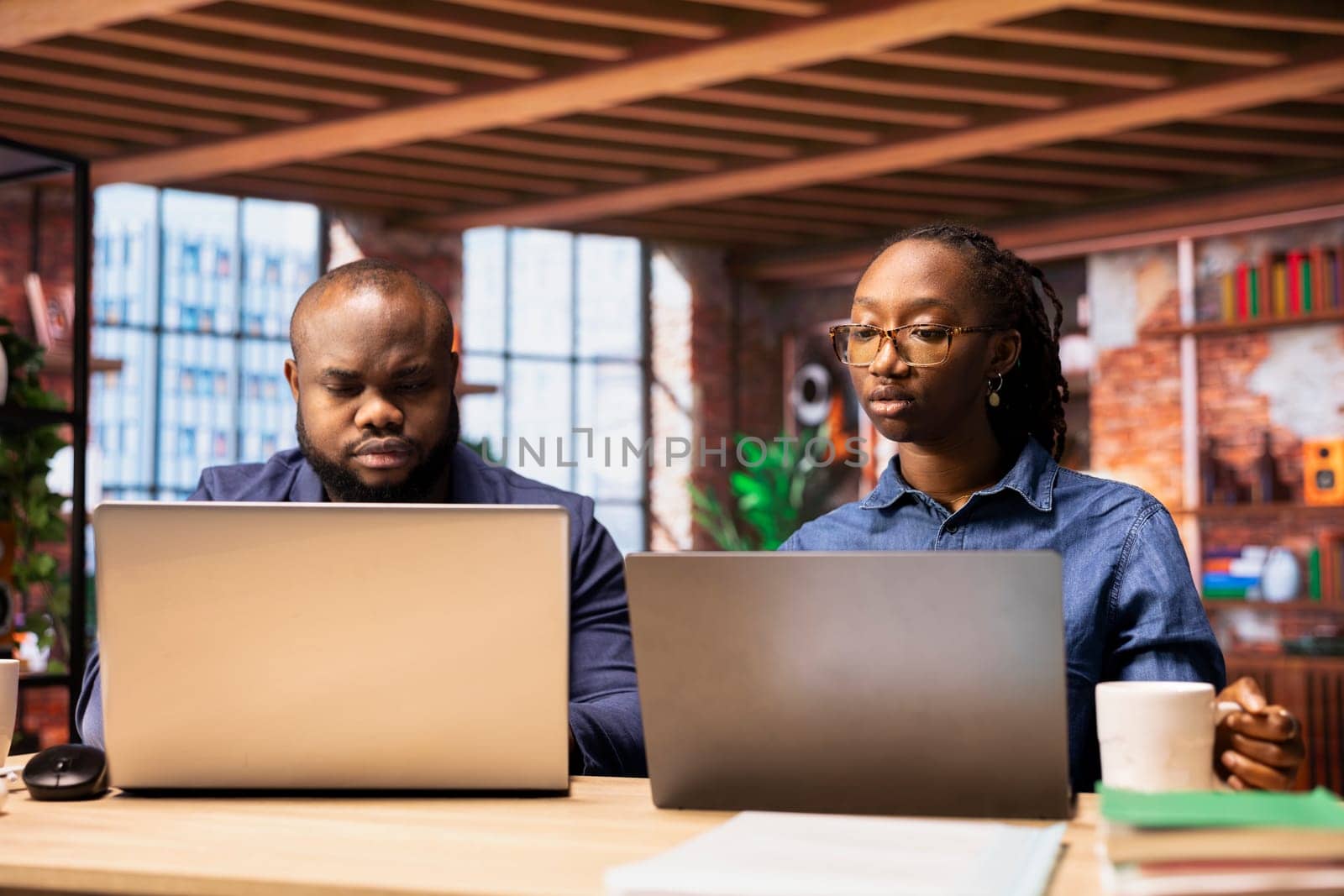 African American couple in their modern home work together on a freelance project, focusing on productivity and strategic planning. Man and woman solving their separate daily tasks.