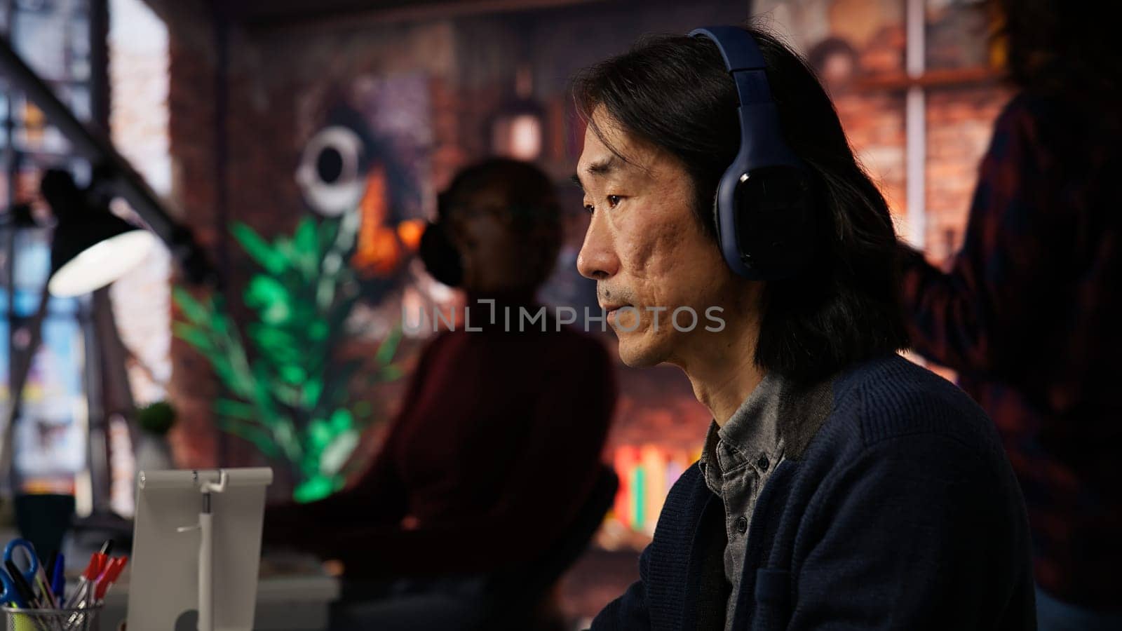 AI startup office chief technology officer listening music while coding application. Senior programmer wearing headphones while working in artificial intelligence software development agency, camera B