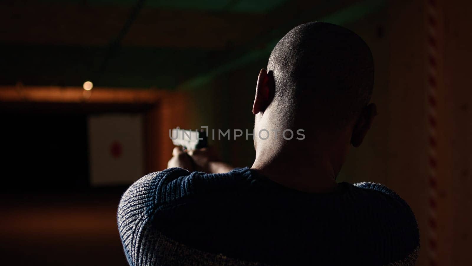 Shooting gallery customer using pistol to hit paper targets with ammo. Close up shot of man at professional firing range facility shooting bullseyes, enjoying using weapons, camera A