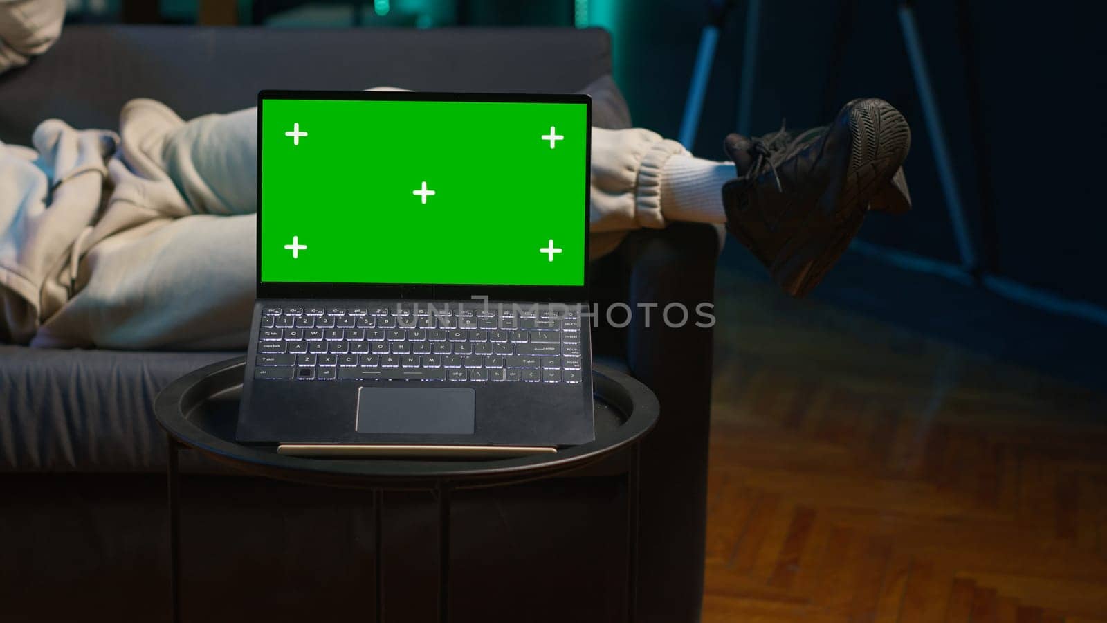 African american freelancer laying on the couch with music next to mockup display on pc, feeling happy with flexible work schedule at home. Young adult uses his tablet relaxing on sofa. Camera A.