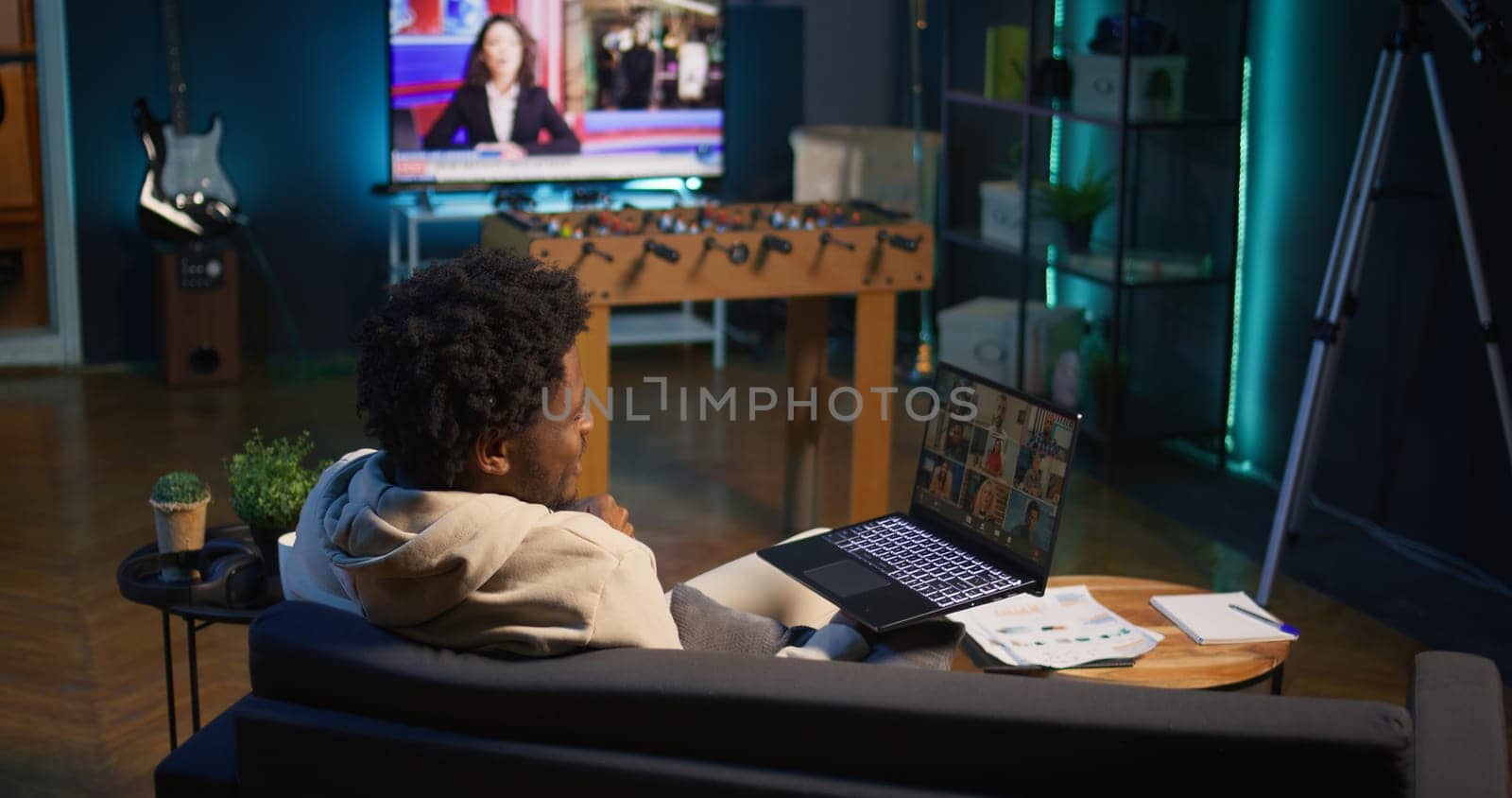Confident male speaker greeting colleagues on a video conference meeting, enjoying benefits of online remote communication in cozy loft. Young black adult hosting virtual discussion. Camera B.