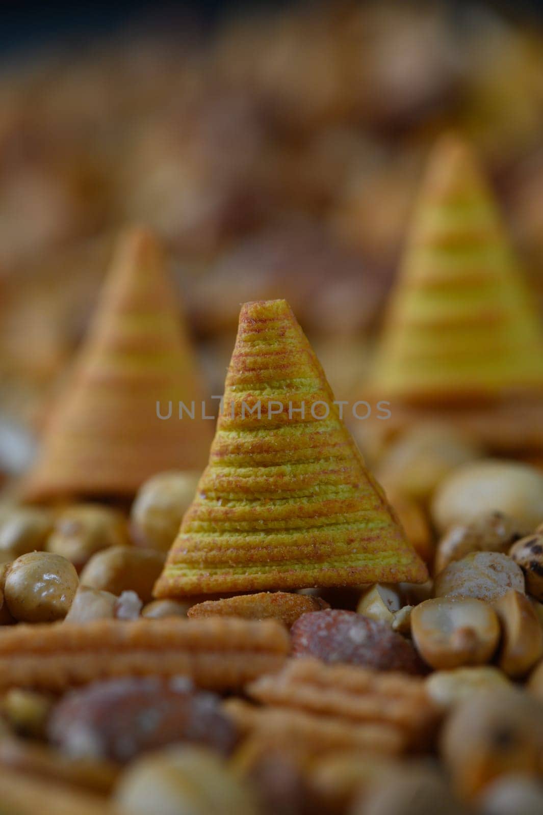 Vibrant conical snacks rise among a colorful display of assorted nuts and seeds, creating an eye-catching centerpiece for a lively gathering full of flavors and joy.