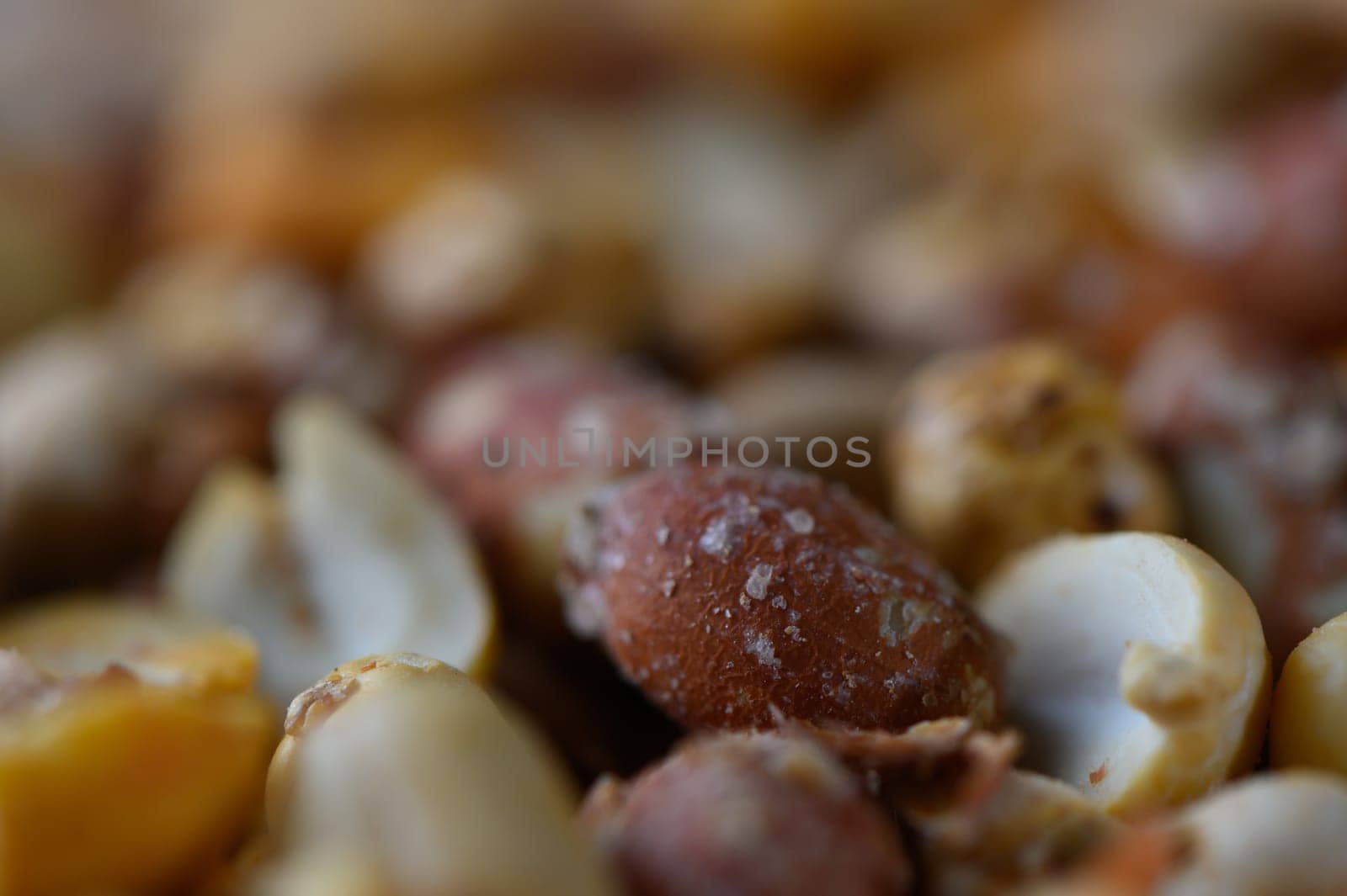 A colorful assortment of roasted nuts fills the frame, showcasing textures and hues that invite sharing. This delightful spread offers warmth and joy during an afternoon snack break among friends.