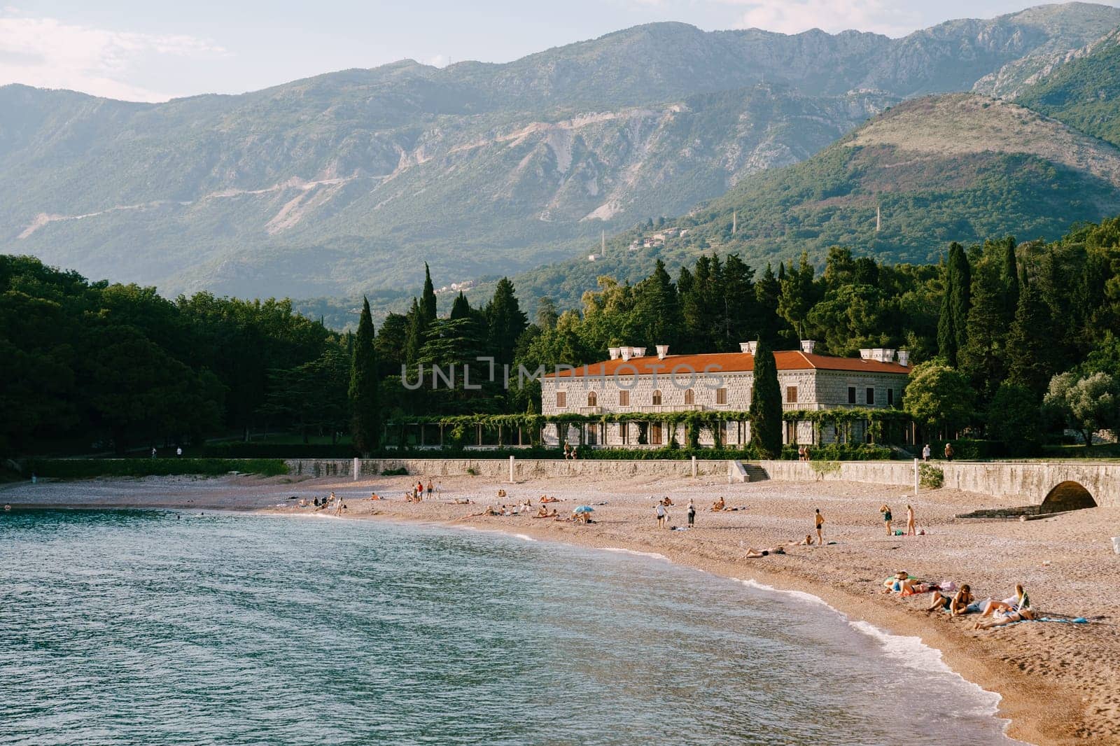 People sunbathe on the sandy beach near Villa Milocer. Montenegro. High quality photo