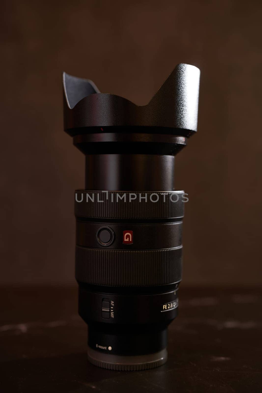 Replacement lens Sony FE 24-70mm for a digital camera with a cap stands on a black table. High quality photo