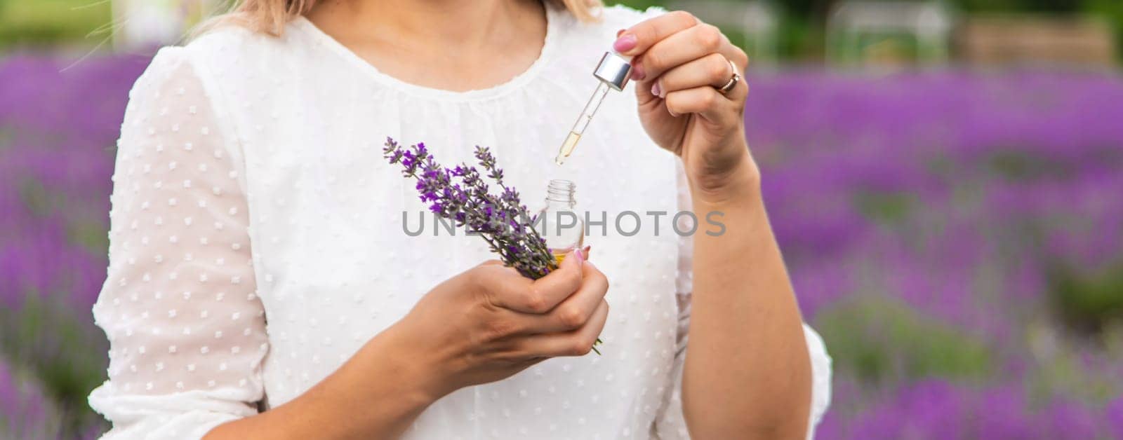 Woman in lavender field holding essential oil in her hands